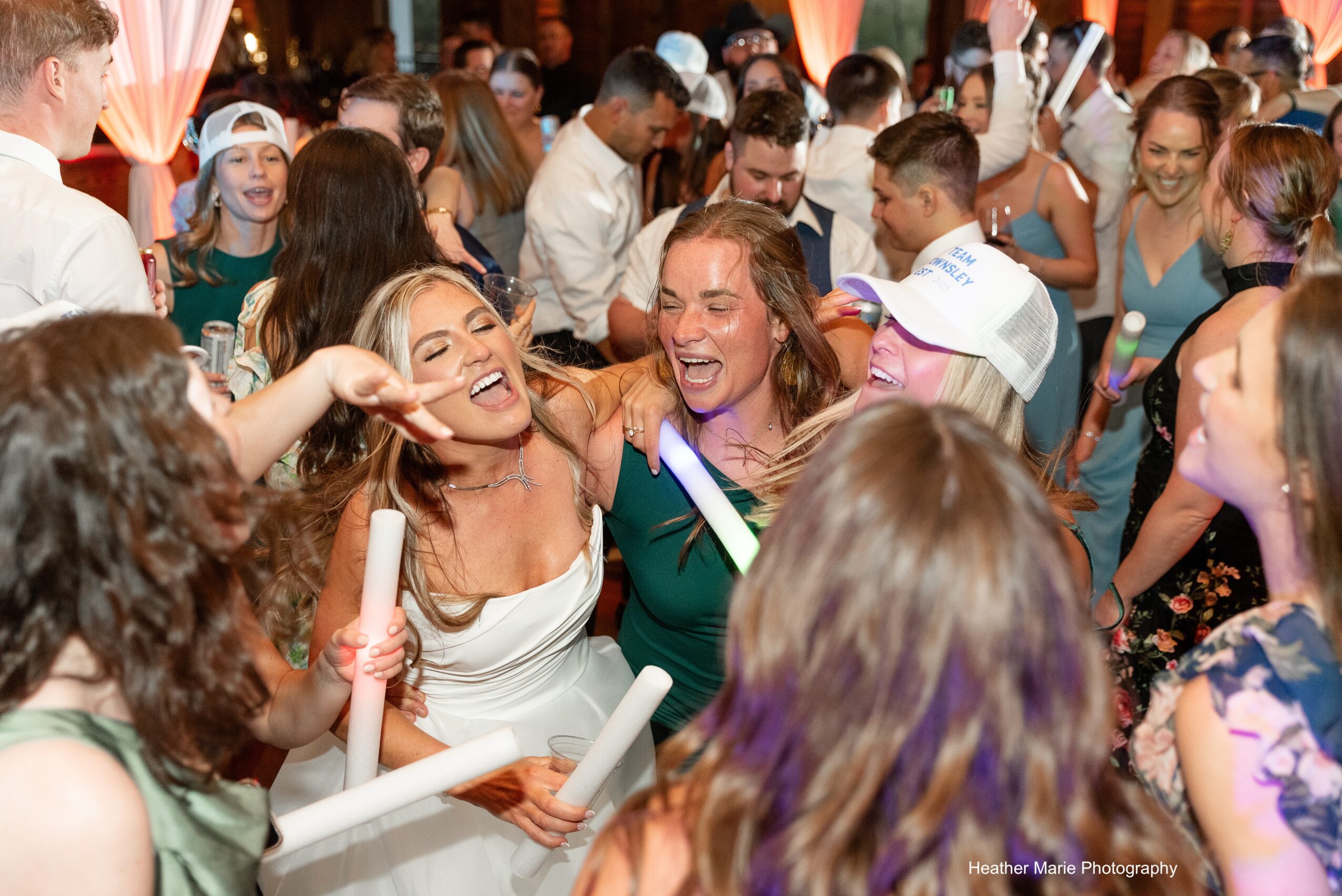 Group of women celebrating and smiling at a lively party with many people in the background.