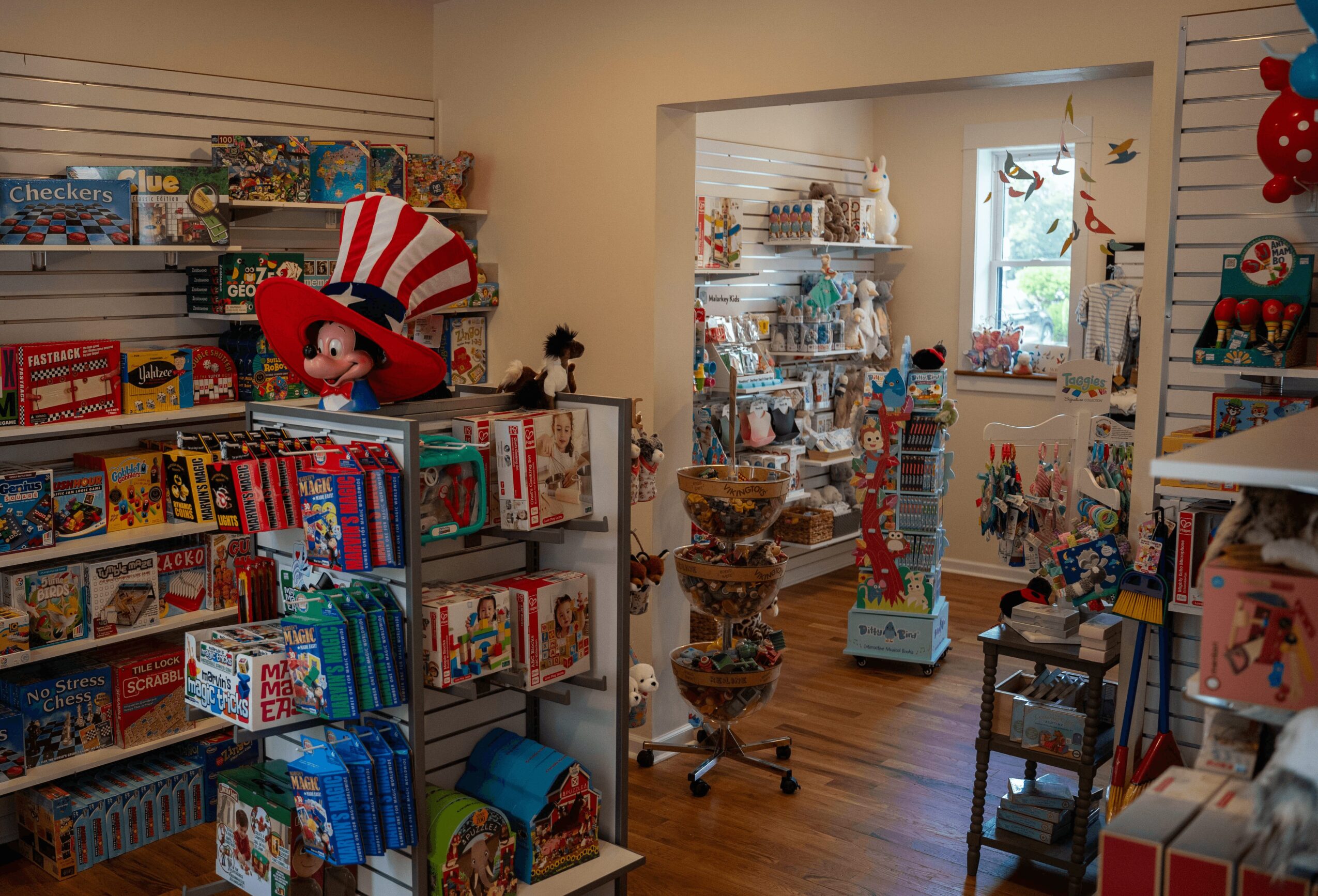 Toy store with shelves filled with games, toys, and a large stuffed character on a shelf, bright and colorful interior.