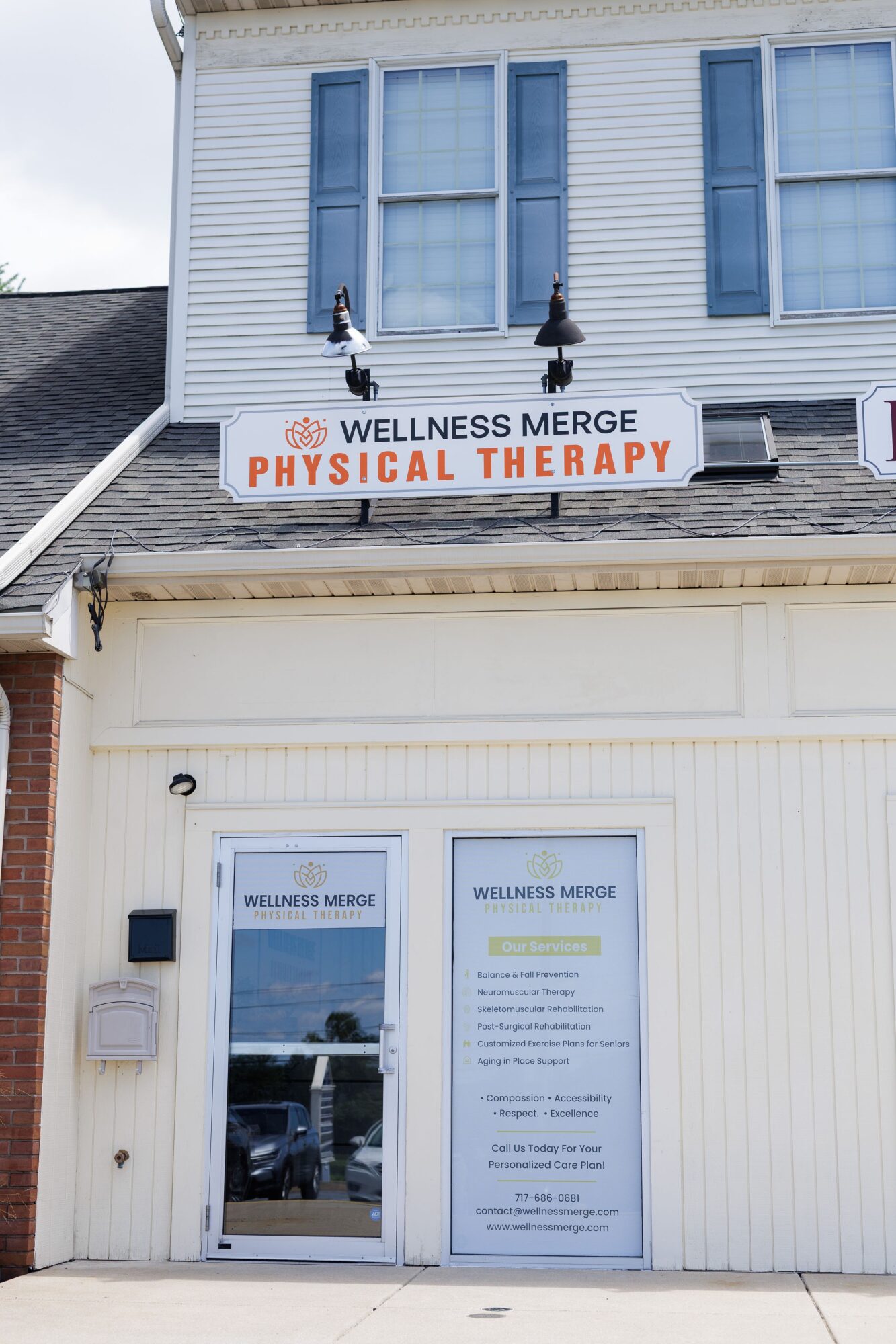 Building with a sign for wellness and physical therapy, two people sitting on a window ledge, glass door with a sign, and a list of services.