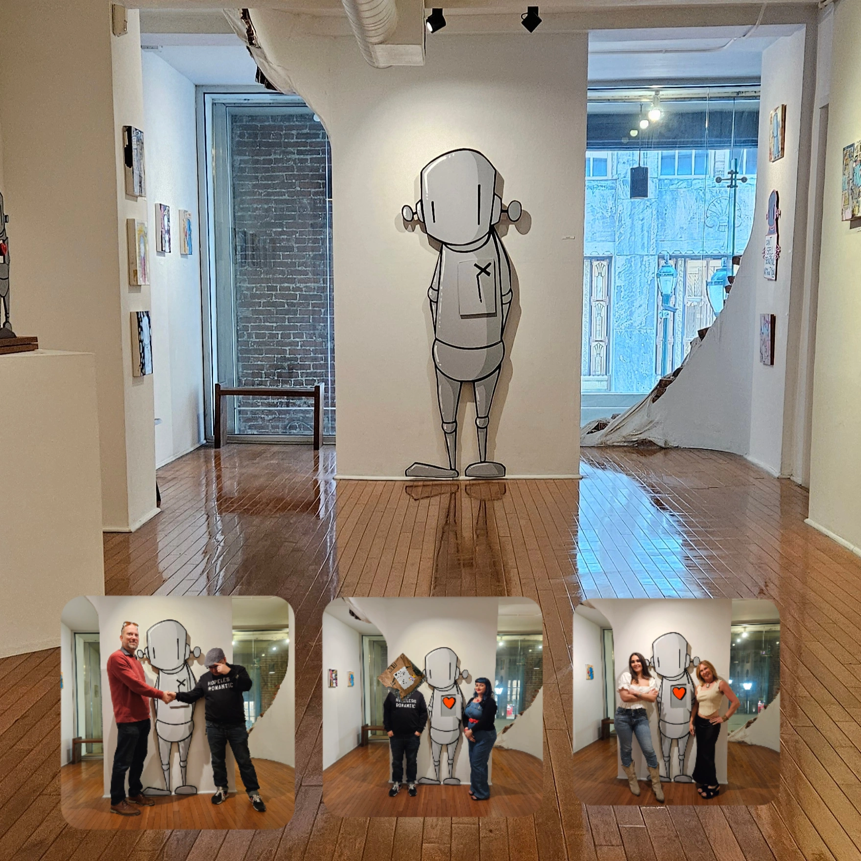 Gallery with artwork of a cartoon character on the wall, three photos of people posing with the character, wooden floor, windows.