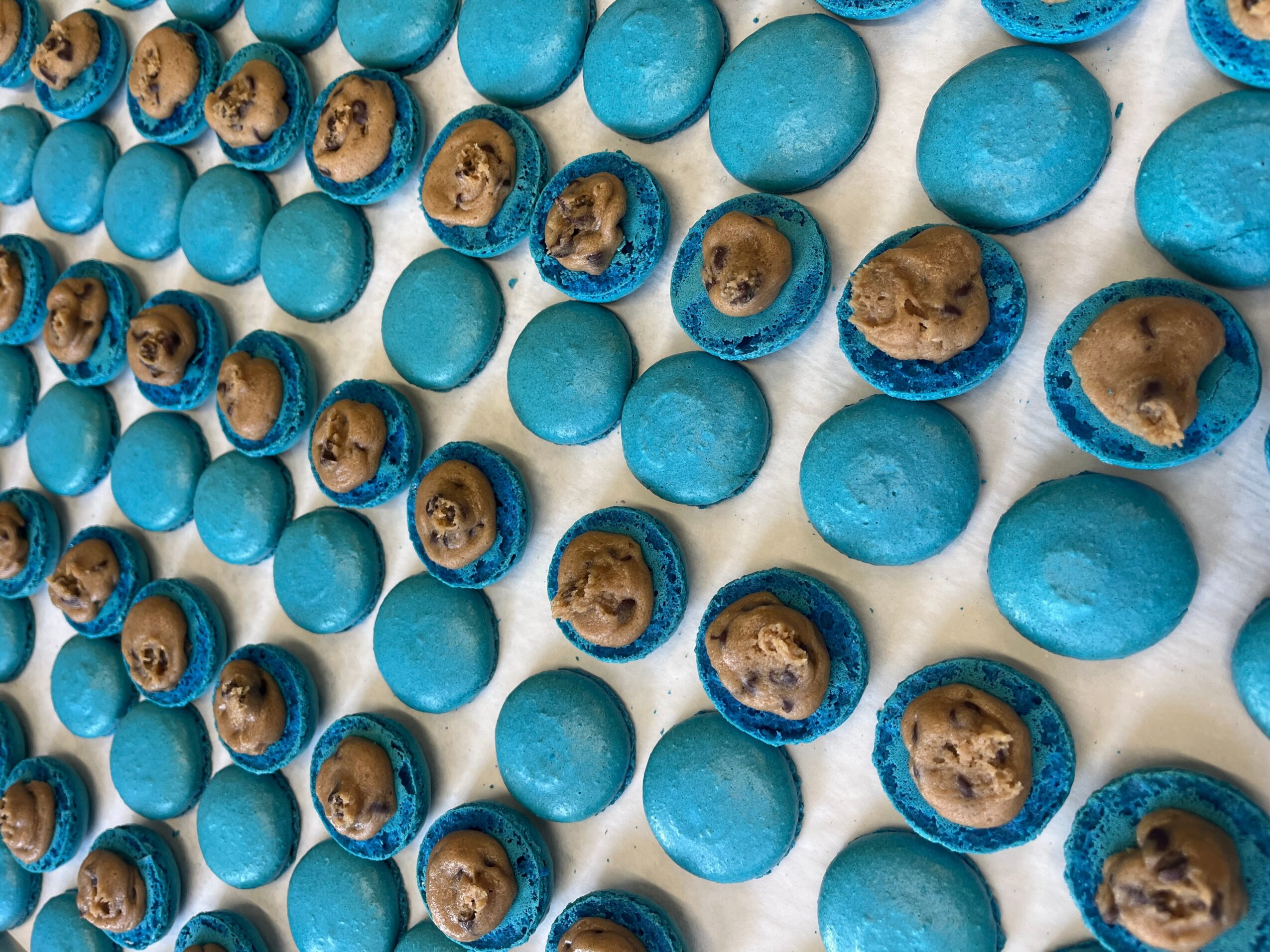 Rows of blue candies with chocolate and cookie filling, arranged in a pattern, viewed from above.