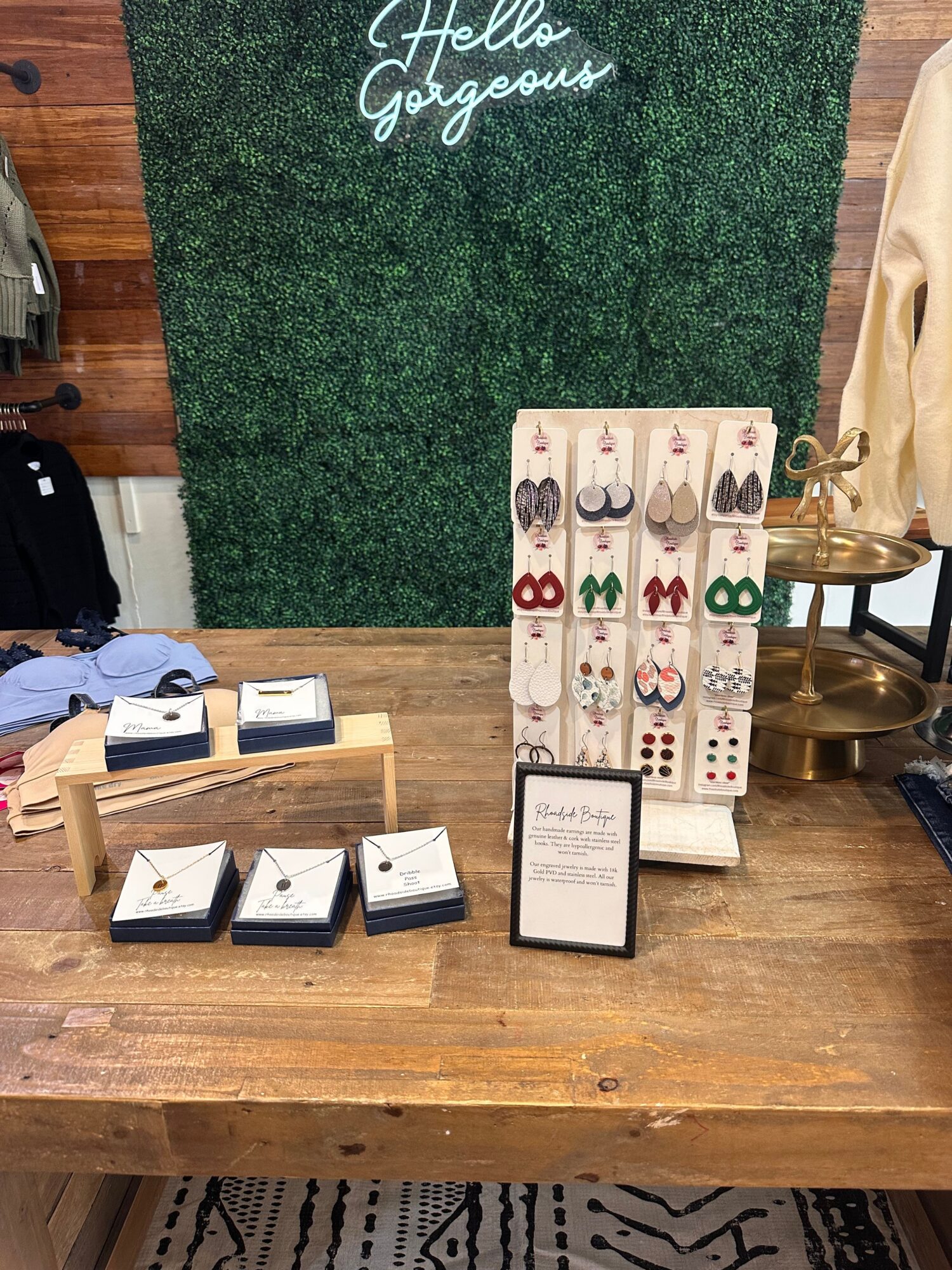 Display of dominoes and small boxes on a wooden table with a green textured background and a sign reading 'Hello Gorgeous'.