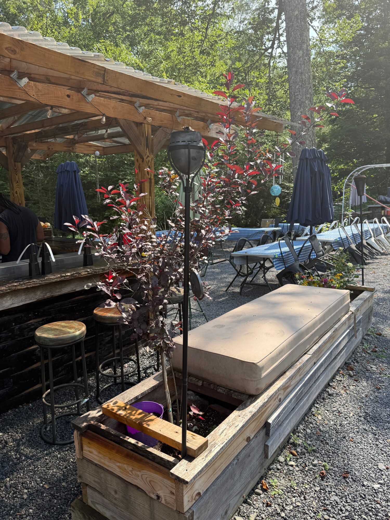 Outdoor scene with a wooden table, plants, and a boat in the background, viewed from the side.