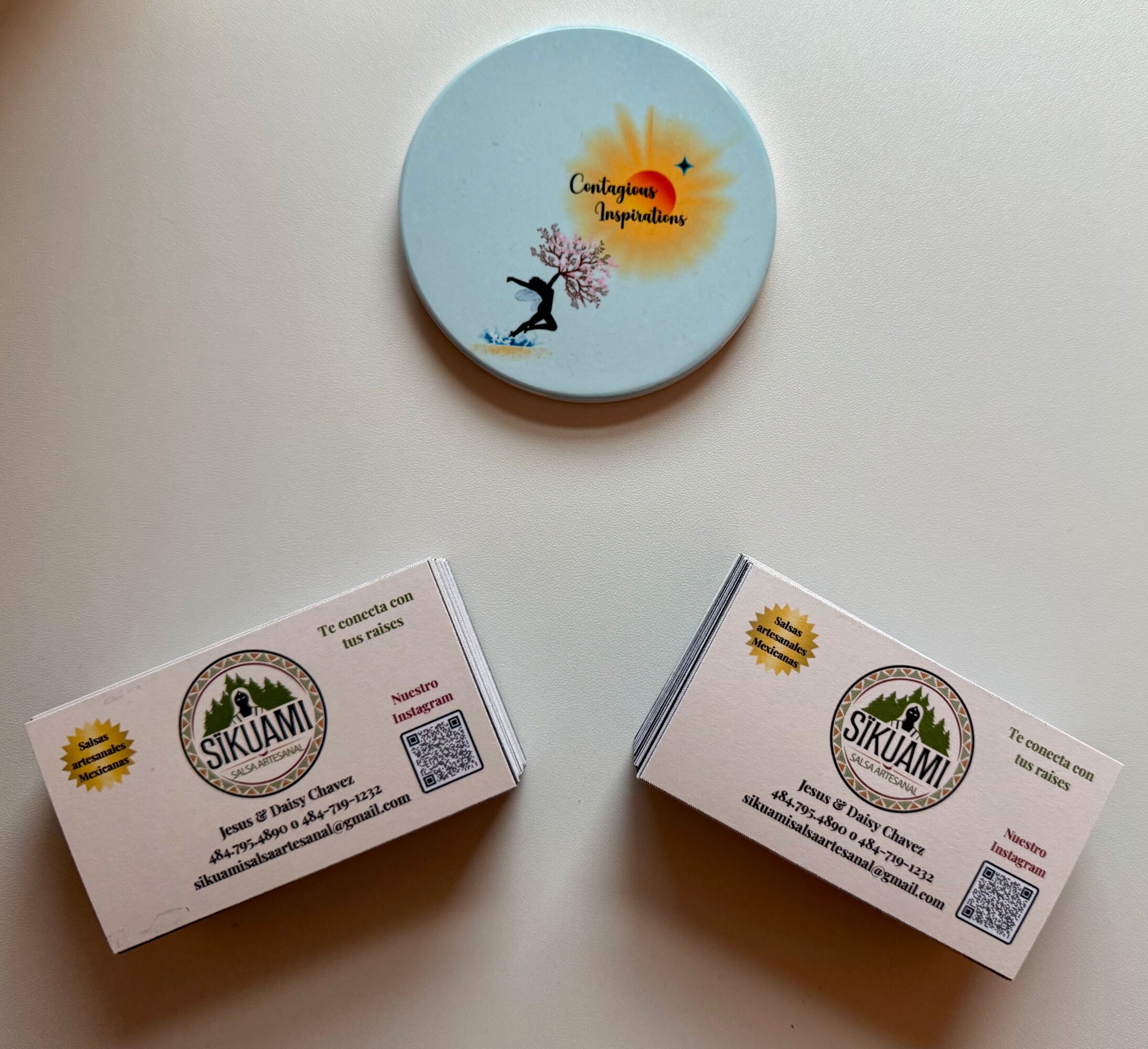 Round container with a design of a person jumping, pink tree, and sun with text. Two boxes with similar labels below.