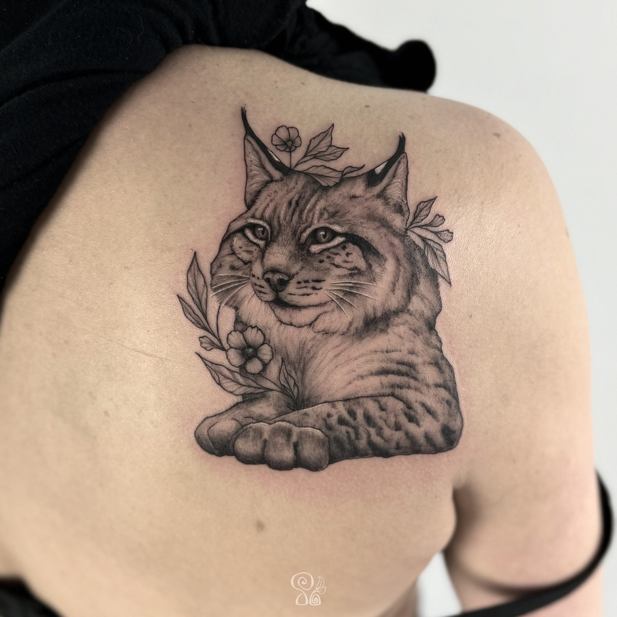 Tattoo of a cat with leaves and berries on shoulder, detailed black and gray line art.