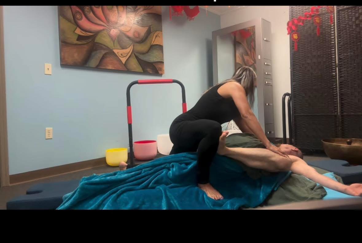 Person lying on a bed receiving a massage from another person in a room with artwork and furniture.