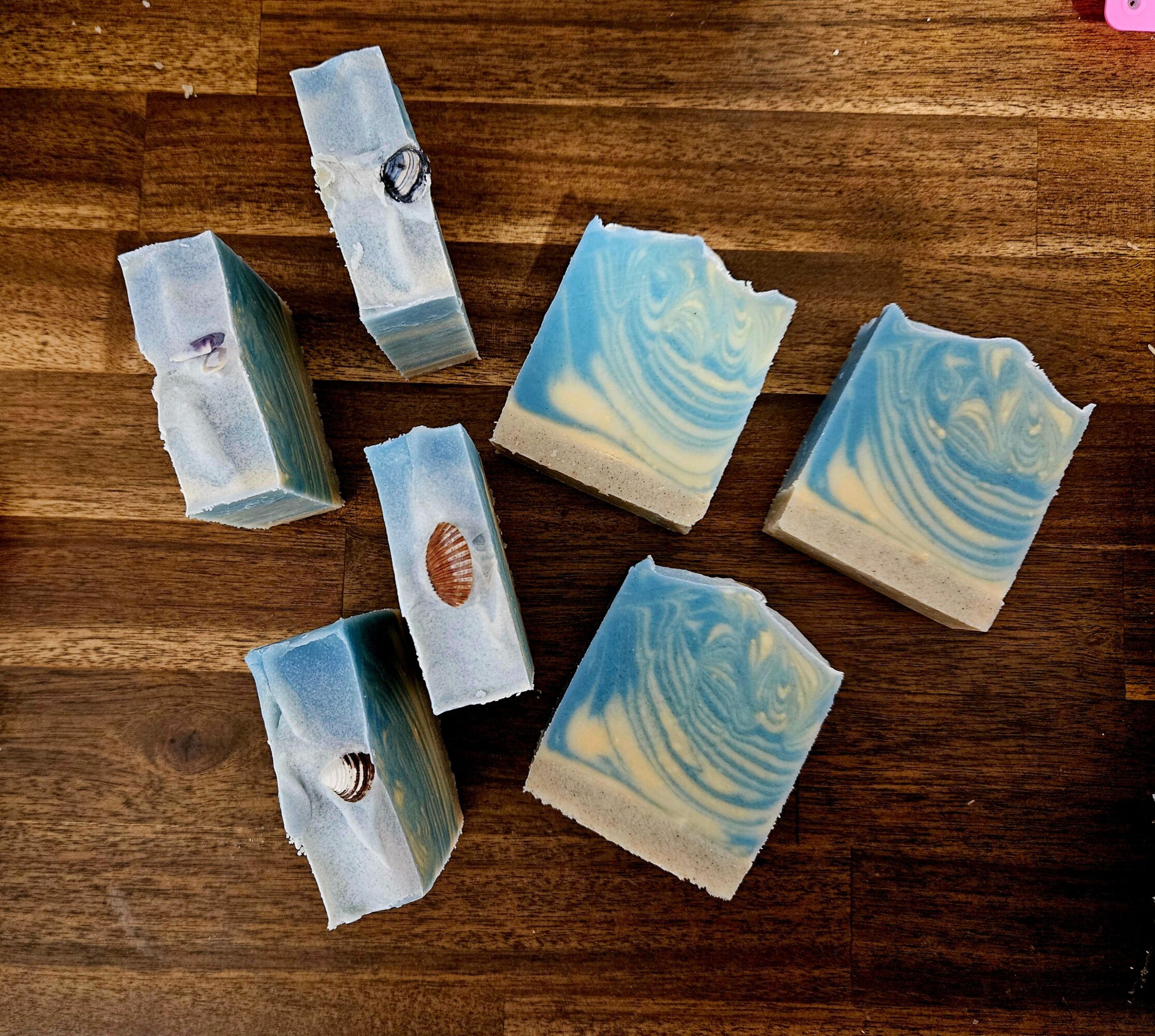 Six soap bars with blue and white swirls on a wooden surface, some with visible logos or designs.