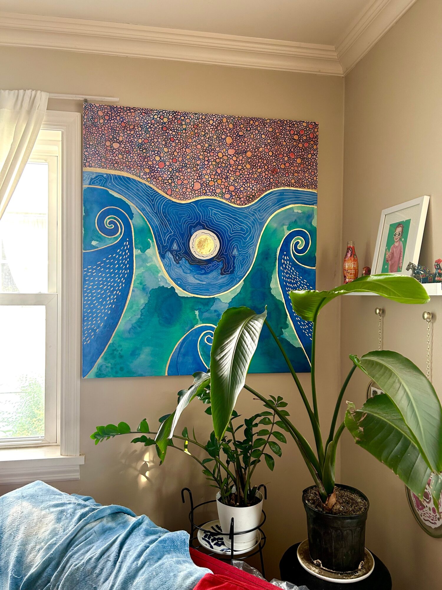 Interior room with a large colorful abstract painting on the wall, plants on a table, and a window with curtains.