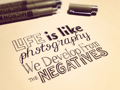 Handwritten quote about photography and negatives with markers nearby, on a light background.