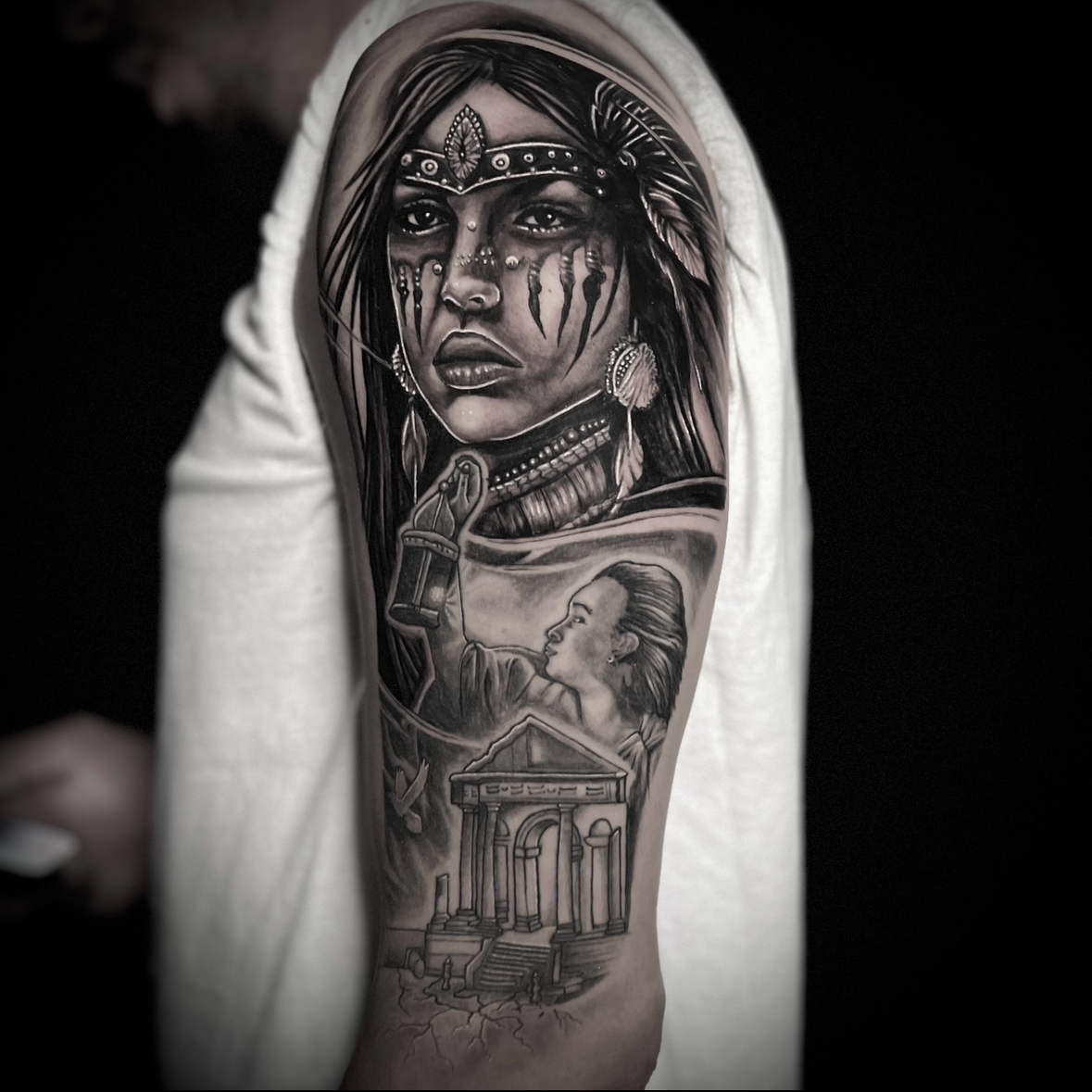 Black and gray tattoo of a woman's face with tribal markings, a woman with a raised arm, and a building with columns.
