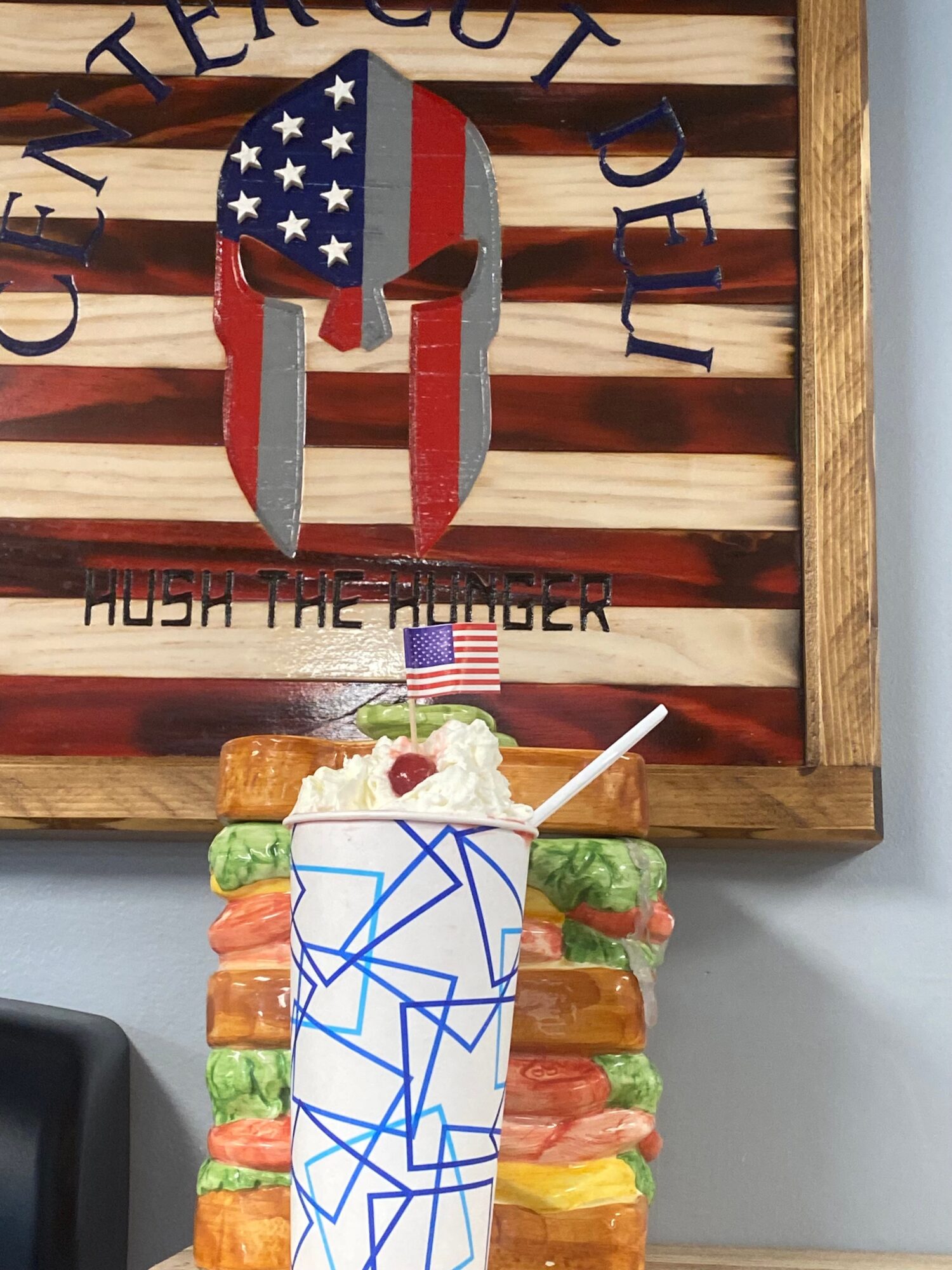 Decorative wooden sign with a Spartan helmet and American flag, and a colorful ice cream sundae with whipped cream and a spoon.