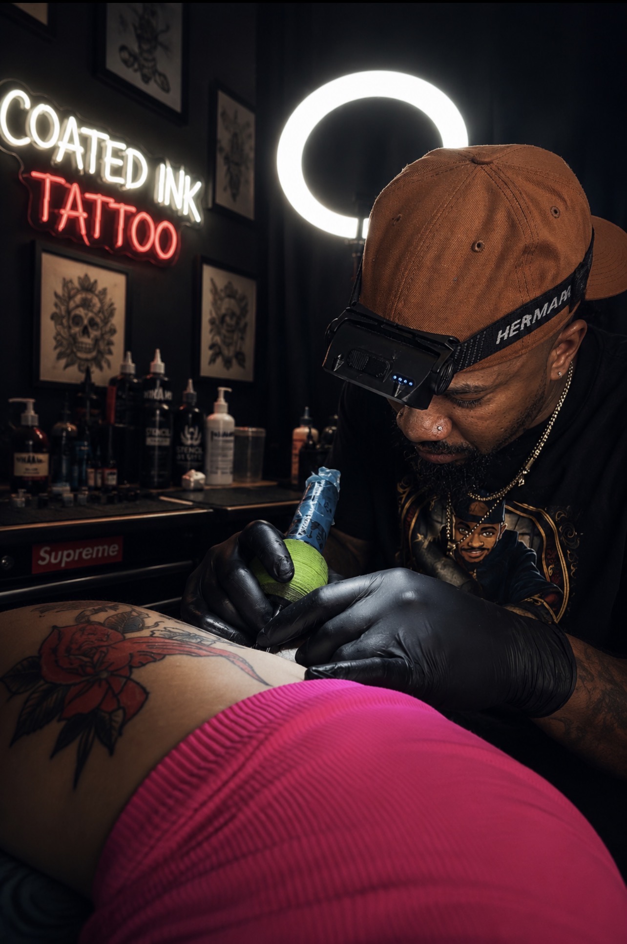 Tattoo artist wearing glasses and gloves tattooing a person's side with a green ink pen, in a tattoo studio.