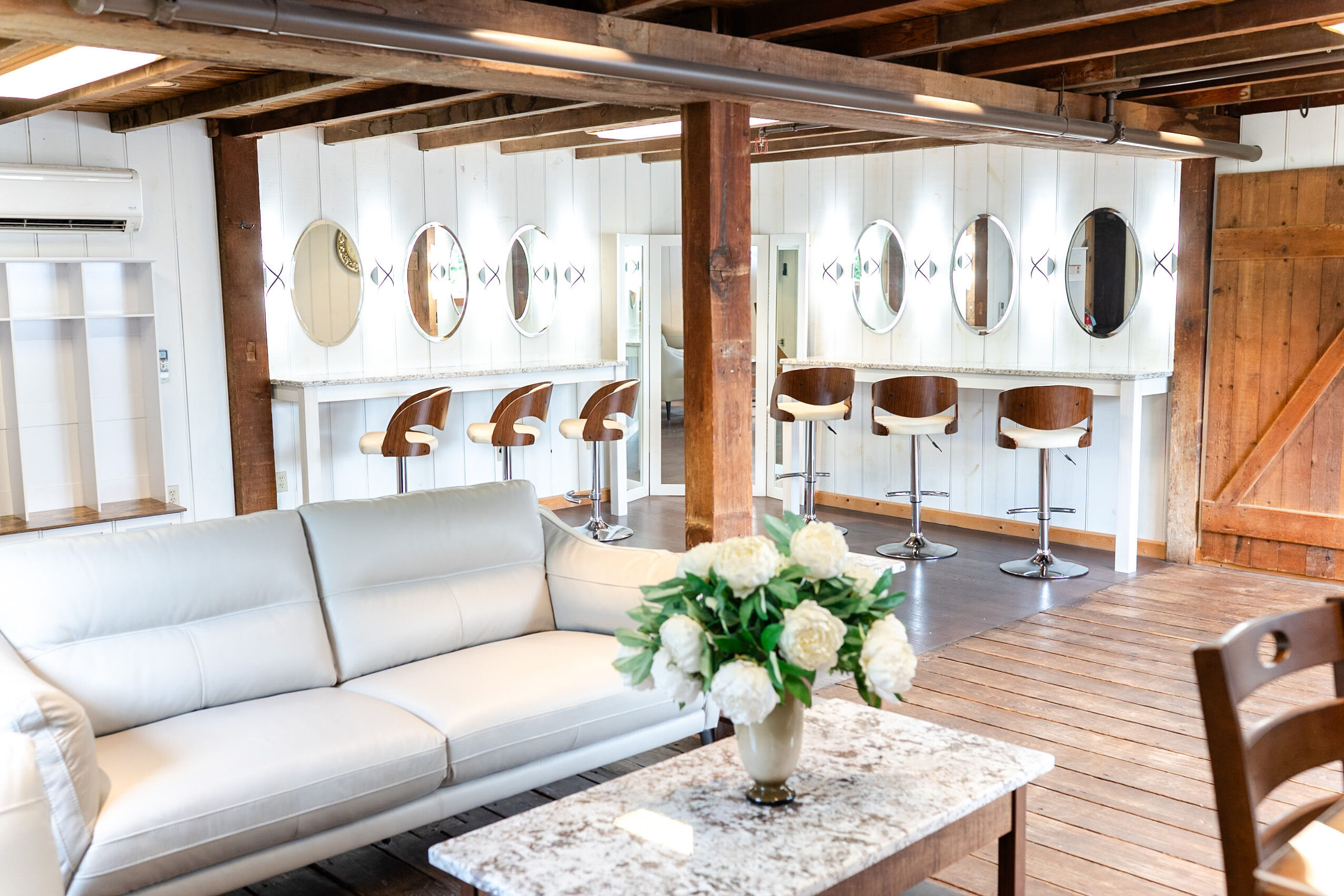 Living room with white sofa, marble coffee table with flowers, and bar stools against a white wall with circular decorations.