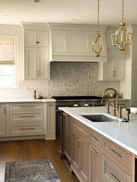 Kitchen with white cabinets, a gray backsplash, and a wooden island with a sink and brass faucet, pendant lights hanging above.