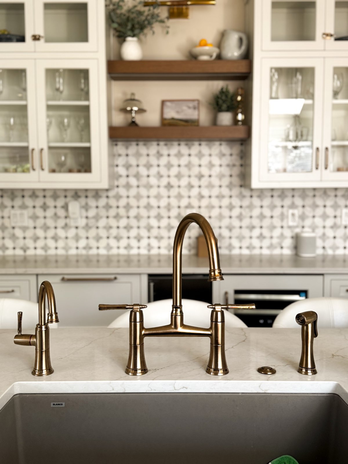 Kitchen with white cabinets, patterned backsplash, and gold-colored faucet and fixtures, viewed from above.