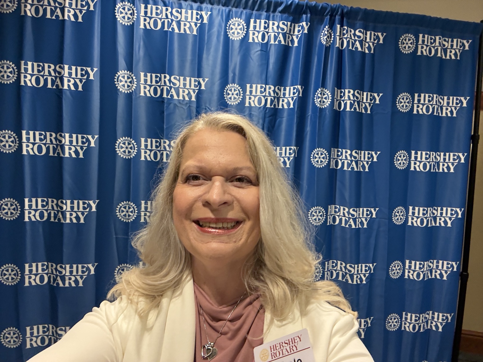 Smiling woman with blonde hair in front of a blue Hershey Rotary backdrop.