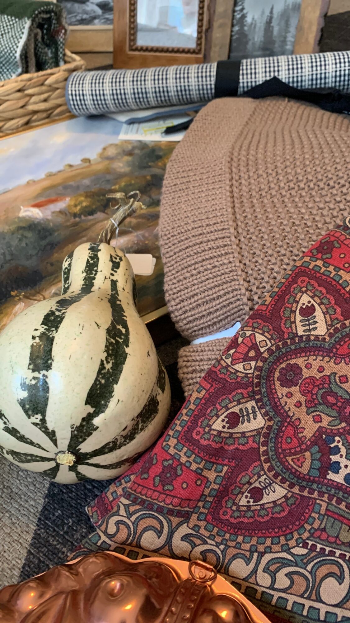 Decorative objects including a striped pumpkin, patterned fabric, and various textiles on a table.