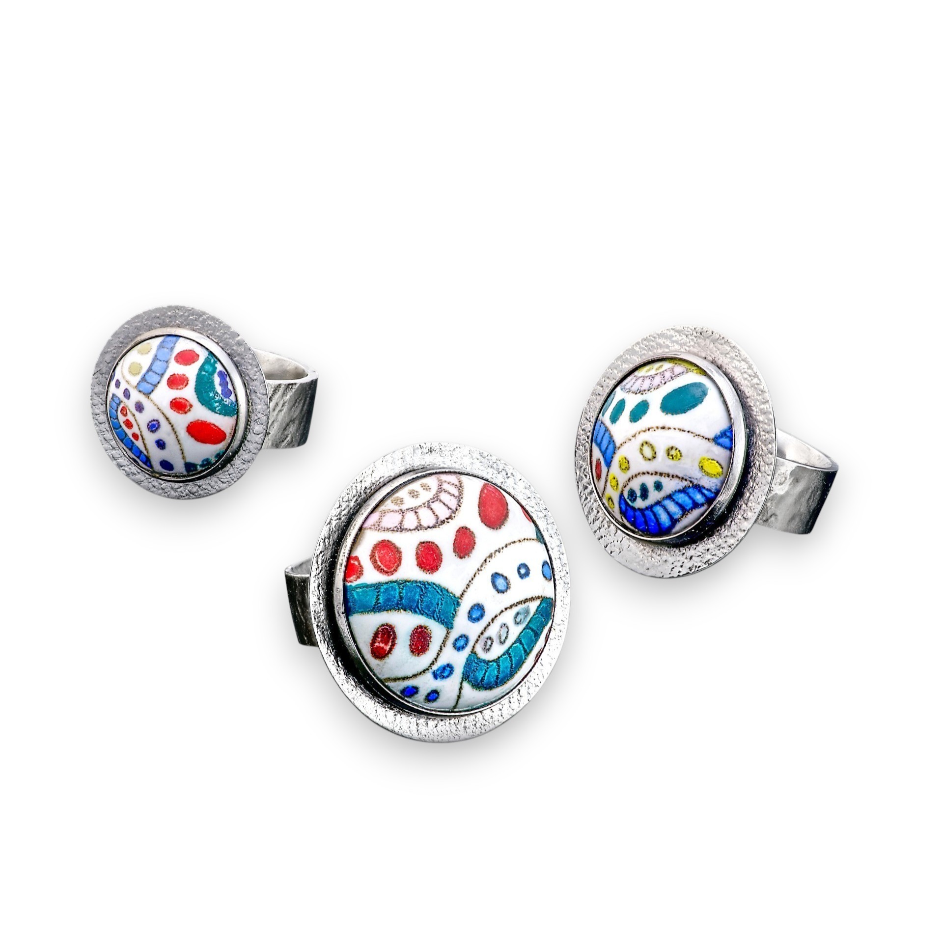 Set of three rings with colorful abstract patterns, one larger and two smaller, on a white background.
