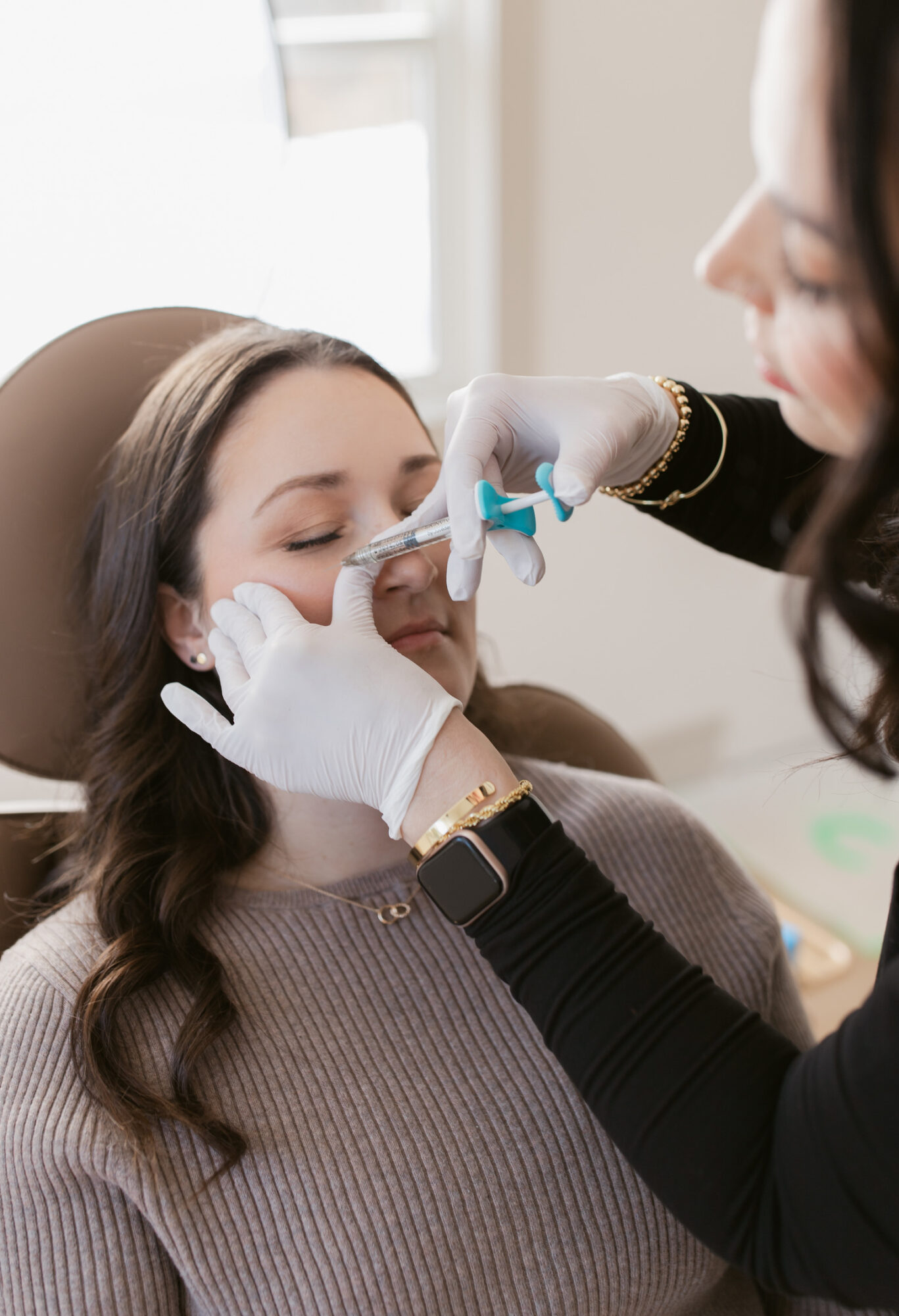 Woman receiving a nasal swab test from healthcare professional wearing gloves, indoors, woman with long brown hair, patient relaxed.
