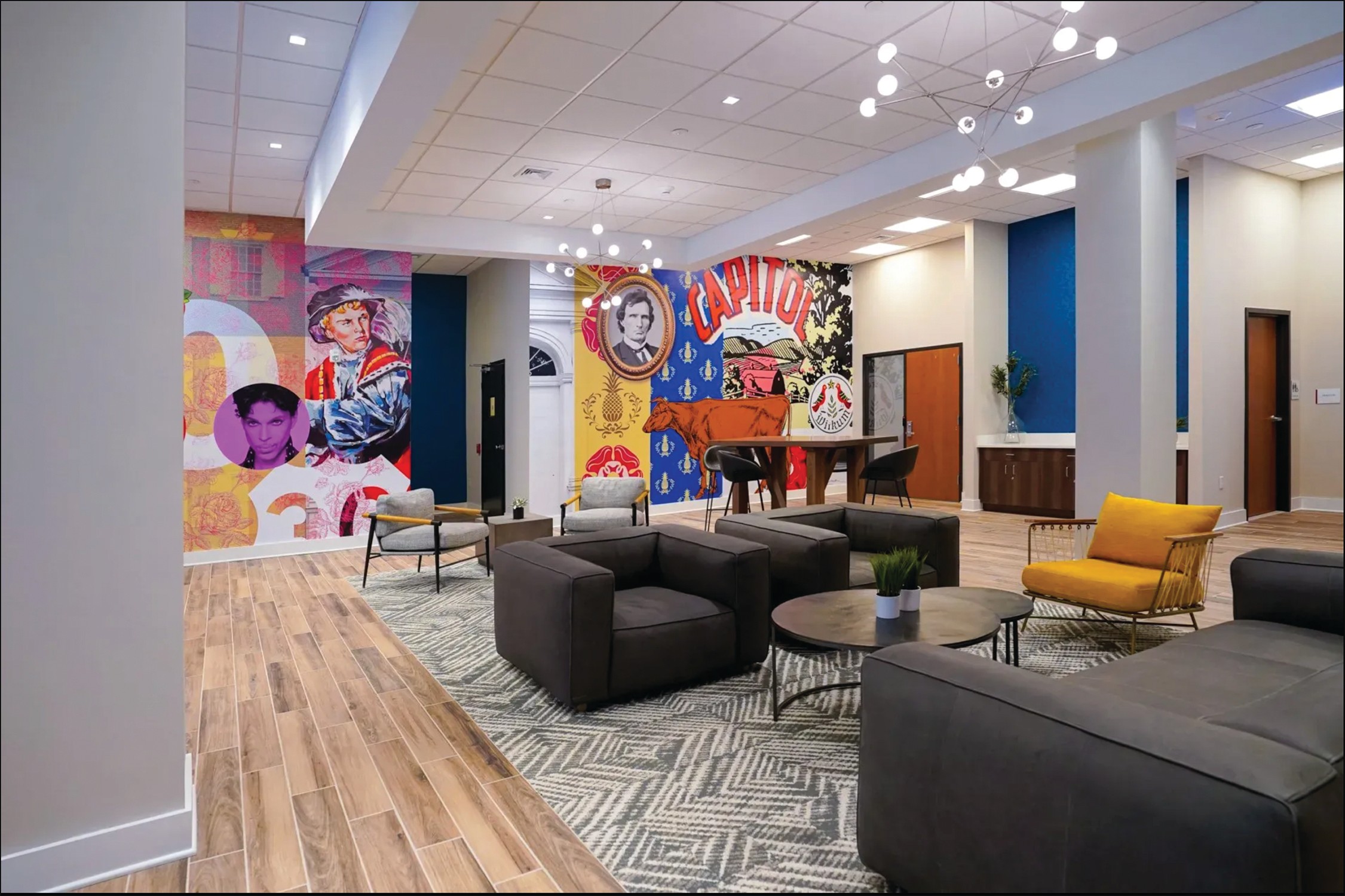Lobby with colorful murals, seating area with sofas and chairs, and a grand piano, wood flooring, and modern decor.