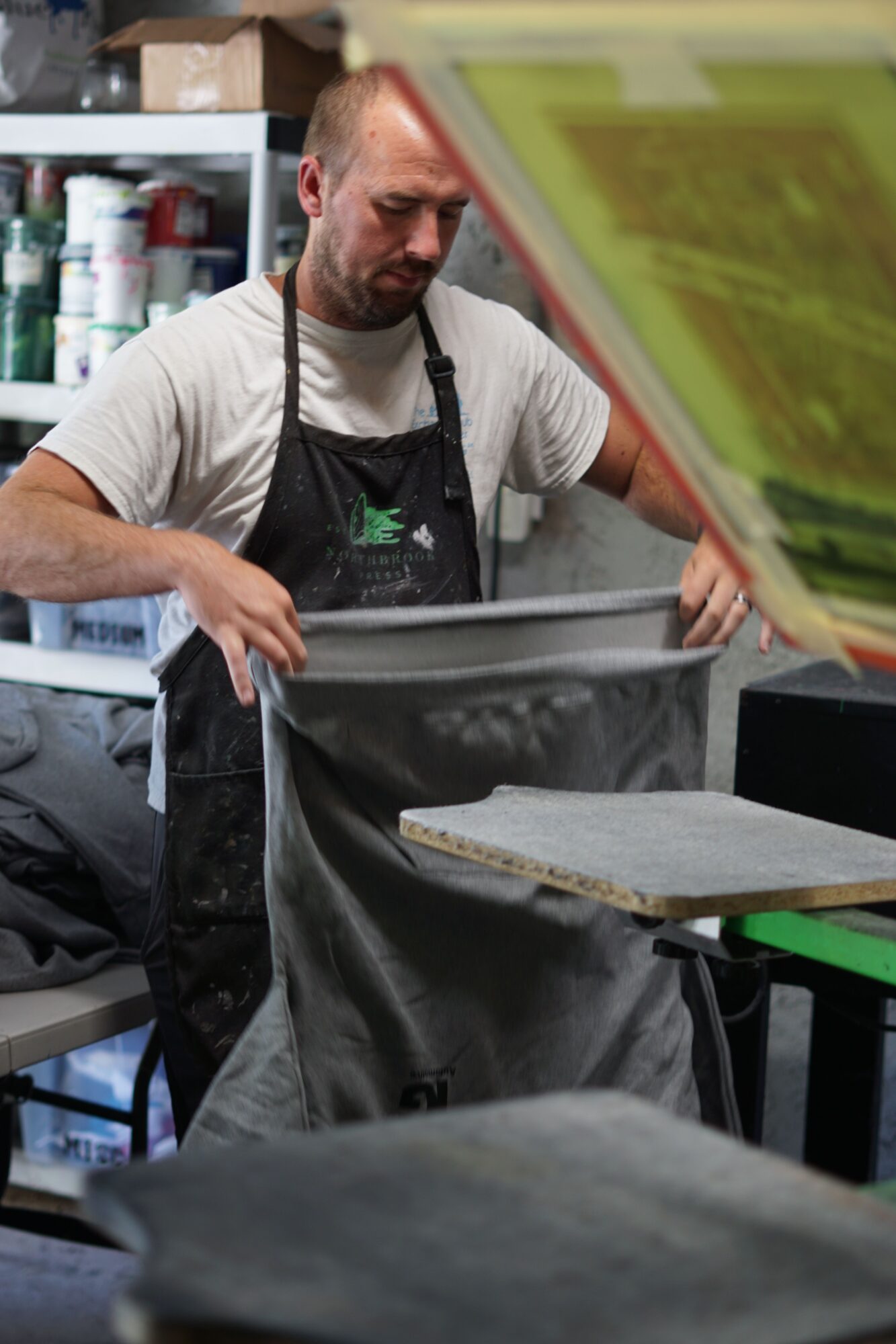 Person working with a large black bag or container in a store or warehouse, shelves with products in background.