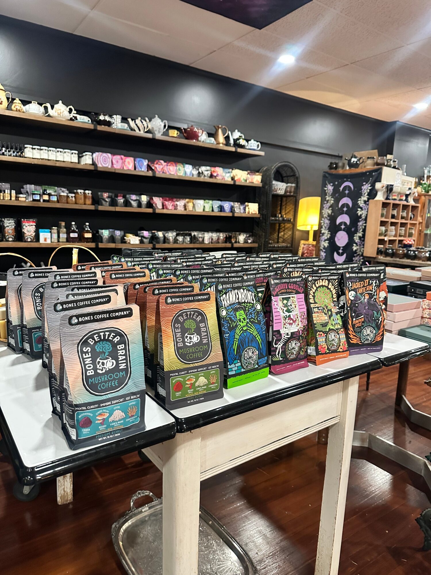 Display of colorful boxed cards and small items on a table, with a black shelf below holding more items.