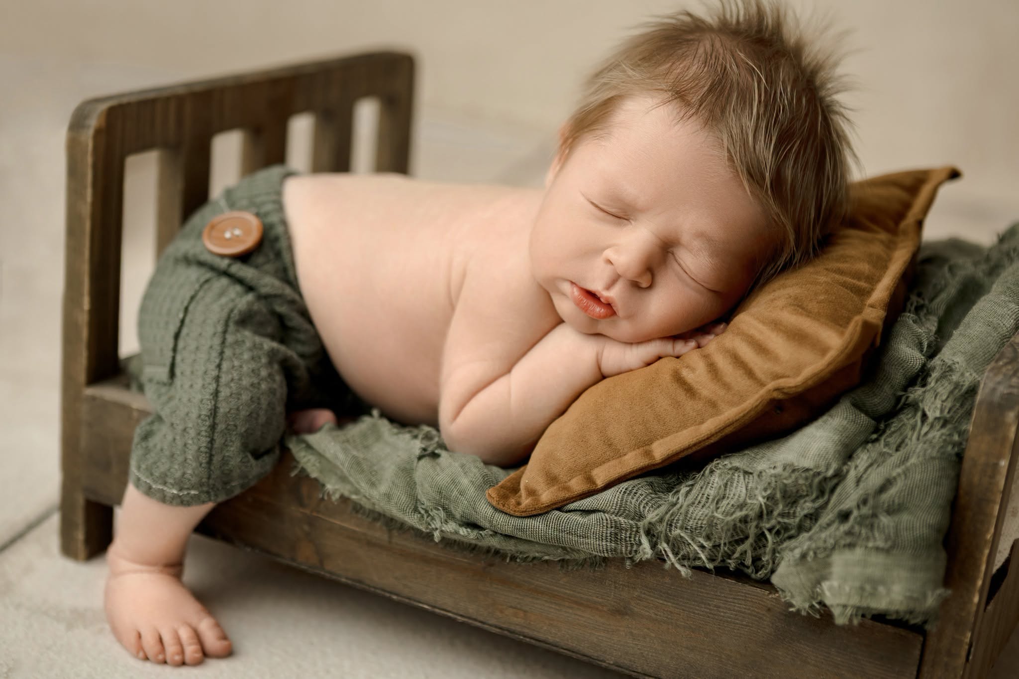 Young child sleeping on a small bed with a brown pillow, lying on their side with head resting on the pillow.
