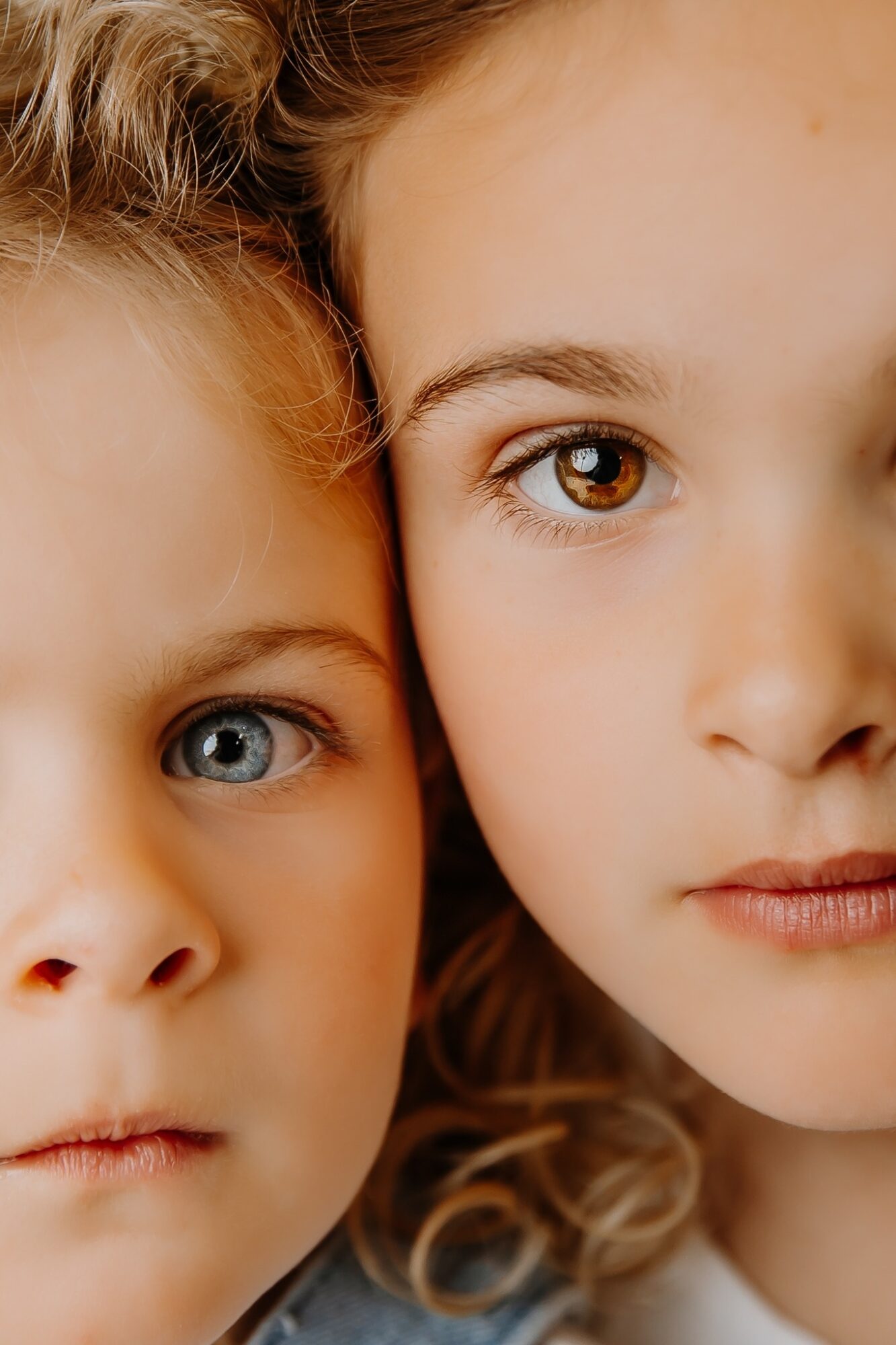 Close-up of two children with light skin and curly hair, showing their eyes and part of their faces.