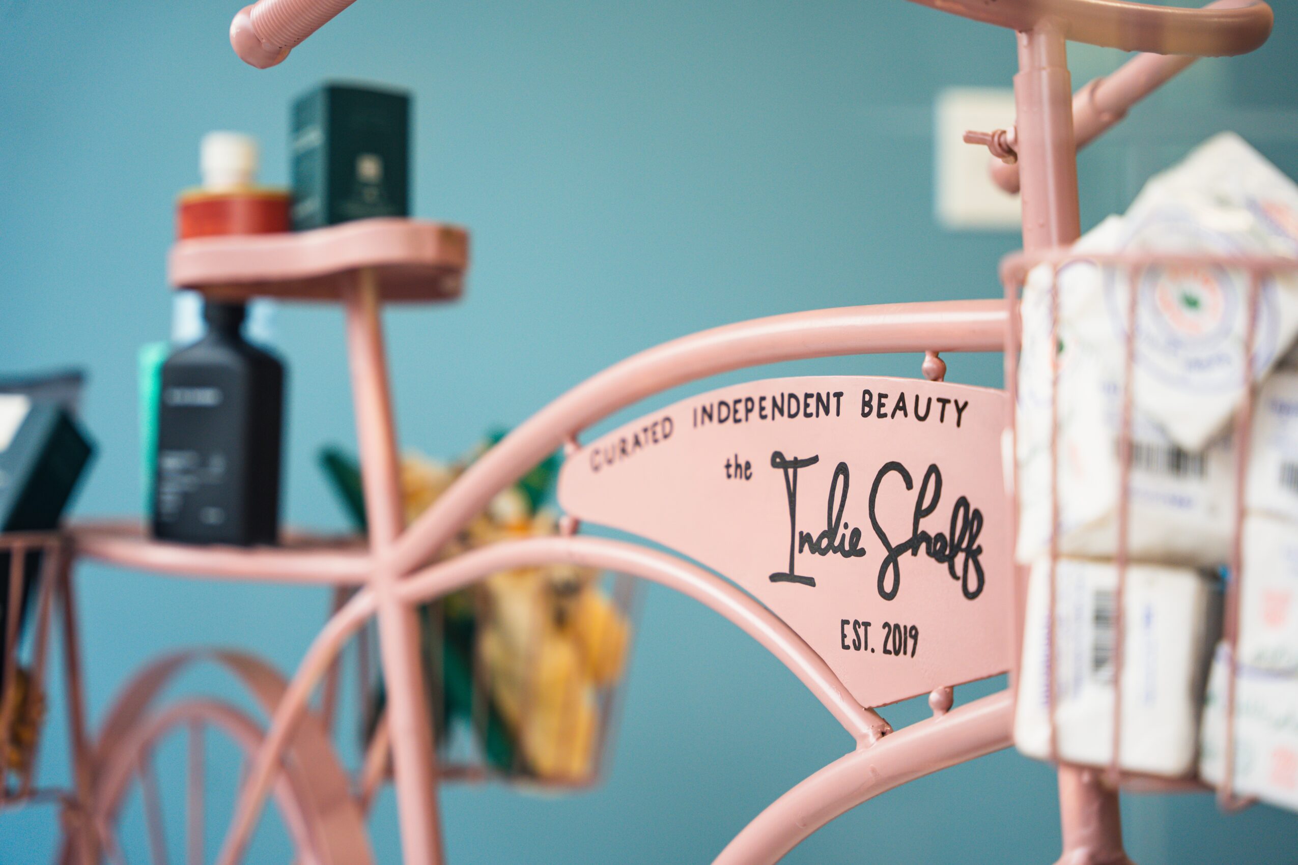 Pink sign with black text reading 'the Ladies Speak' and 'EST. 2019' in a beauty shop interior.