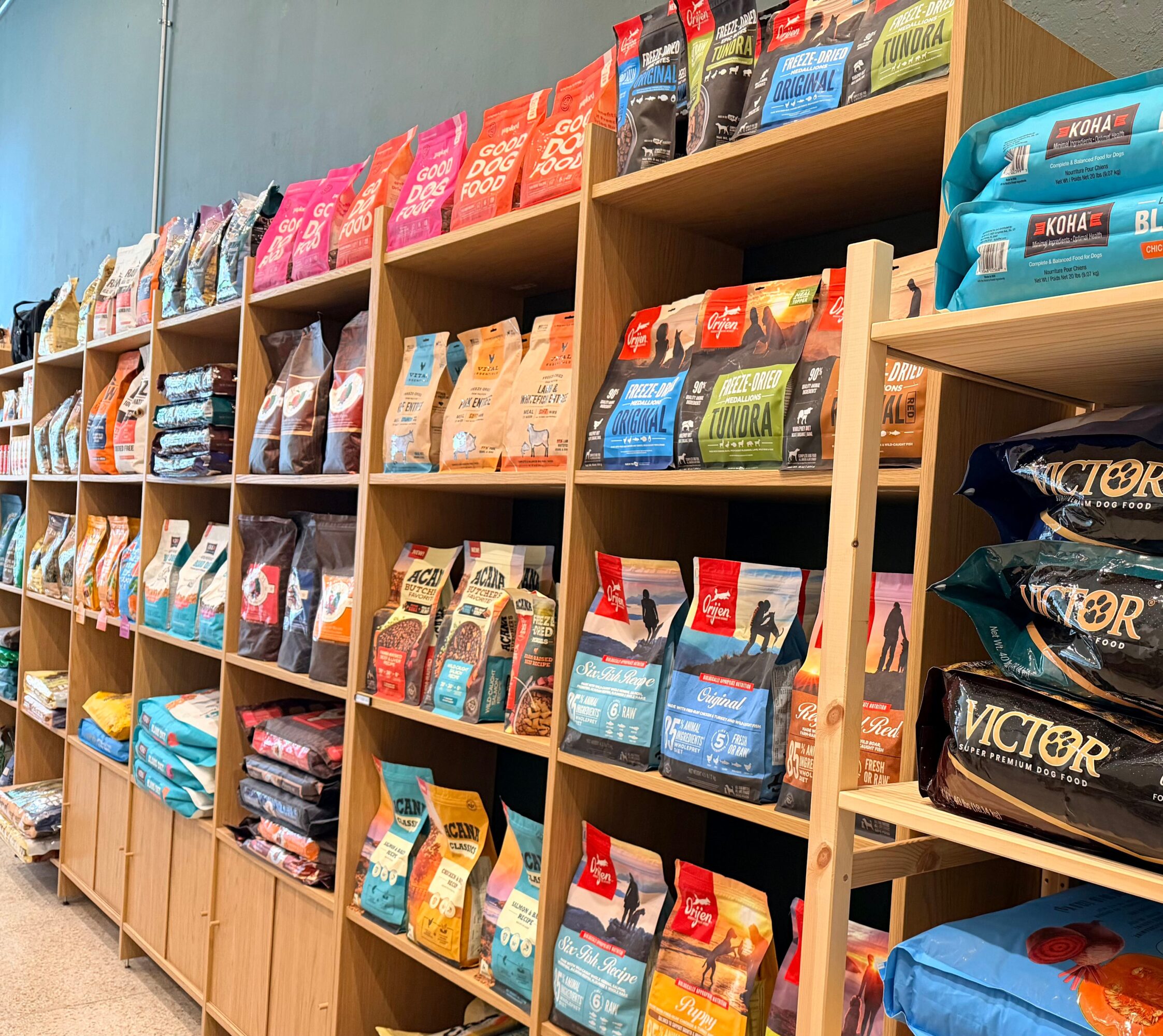 Shelves stocked with various bags of pet food in a store, organized by brand and type.
