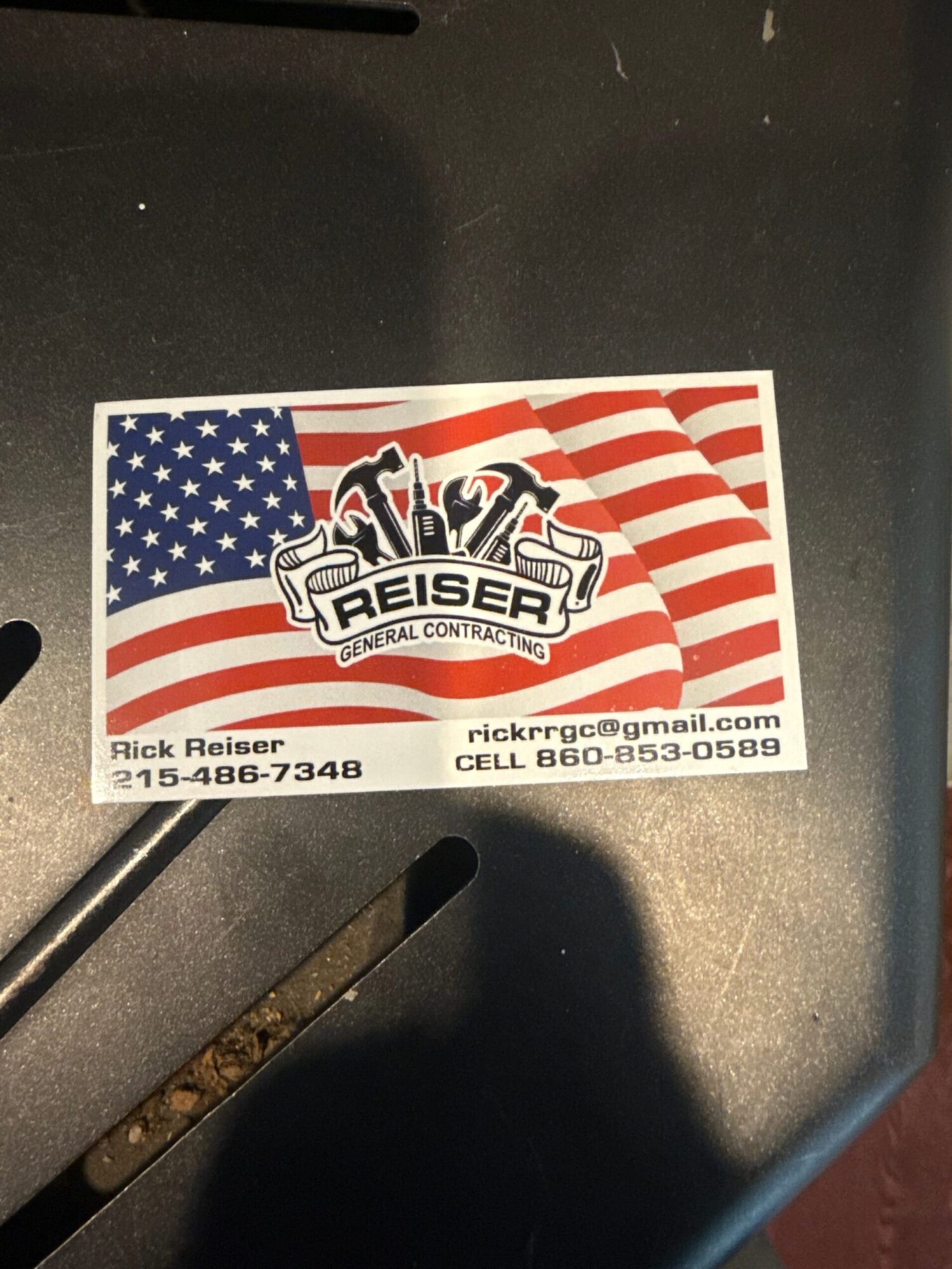 ReiseRebel sticker with American flag and red and white stripes, and a black and white logo, on a black surface.