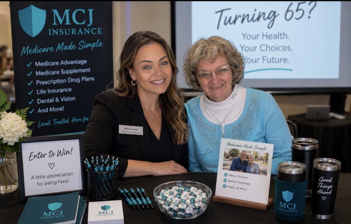 Two women sitting at a table with promotional materials, smiling, in front of a screen about turning 65 and health choices.