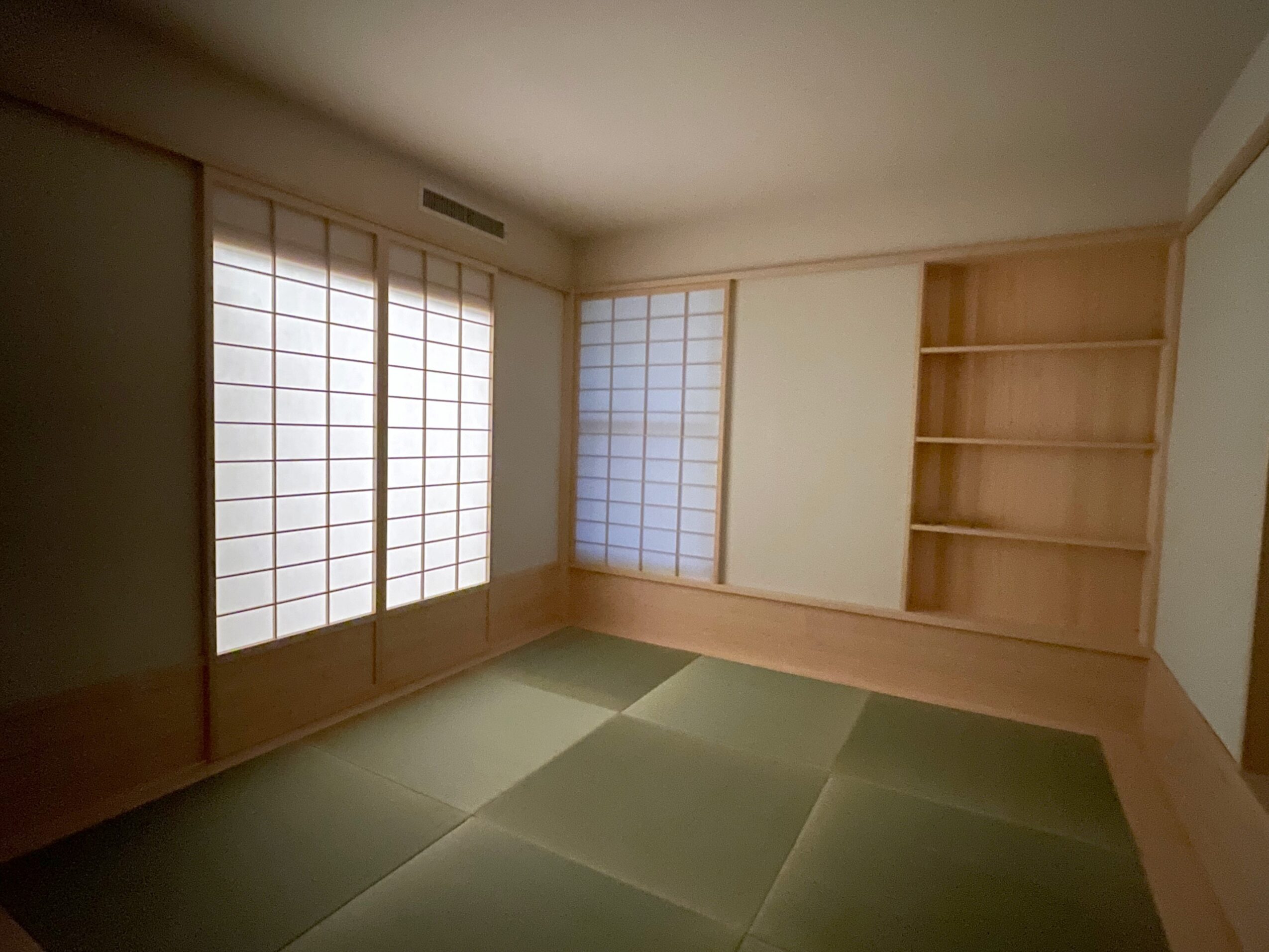 Room with tatami mats, shoji sliding doors, and built-in wooden shelves, minimalistic Japanese-style interior.
