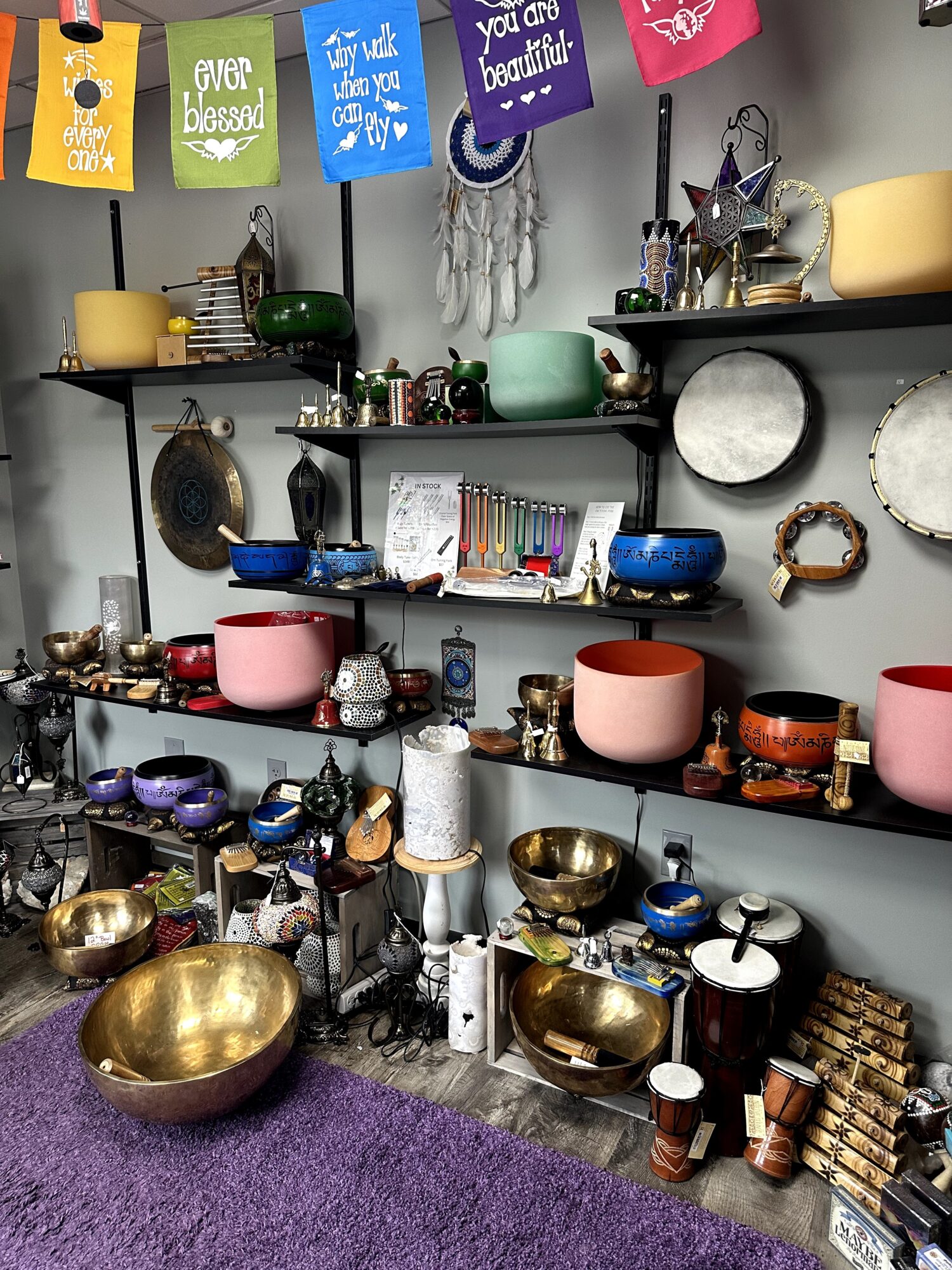 Shelves display colorful bowls, vases, and decorative items with hanging banners above. Purple carpet is visible at the bottom.