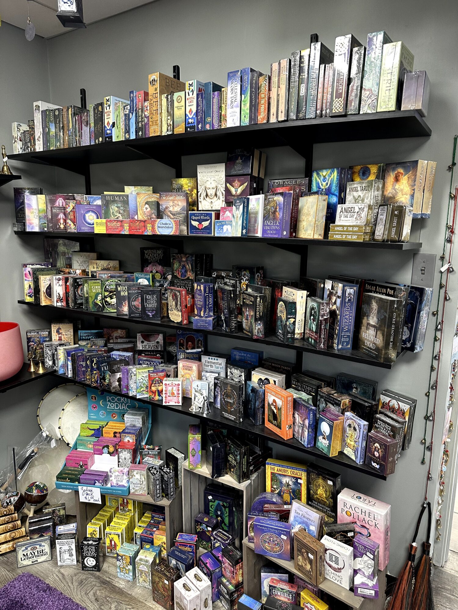 Bookshelves filled with various books and board games, organized on multiple black shelves against a gray wall.