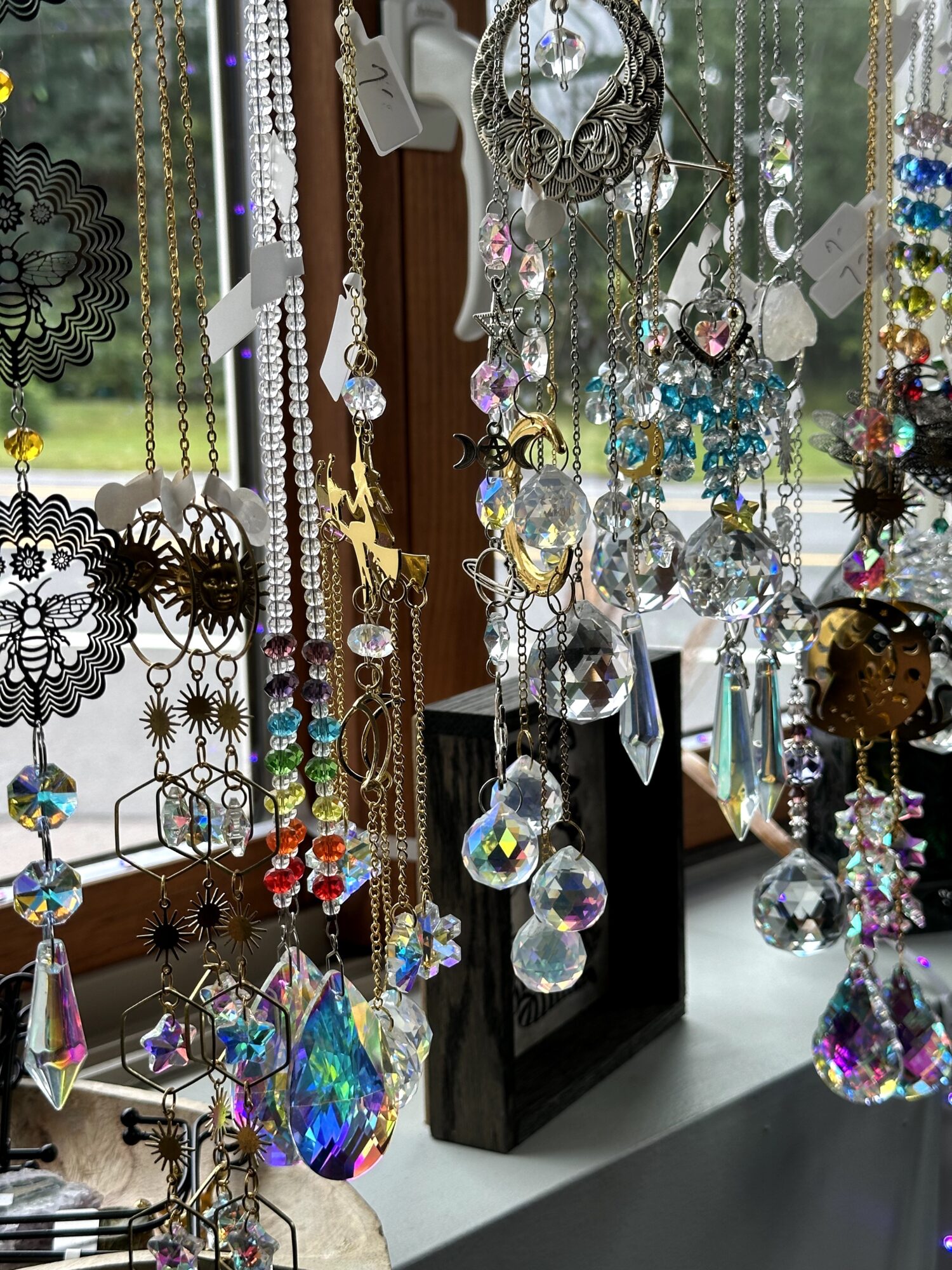 Display of various jewelry and accessories hanging with sunlight through window, including necklaces, earrings, and decorative items.