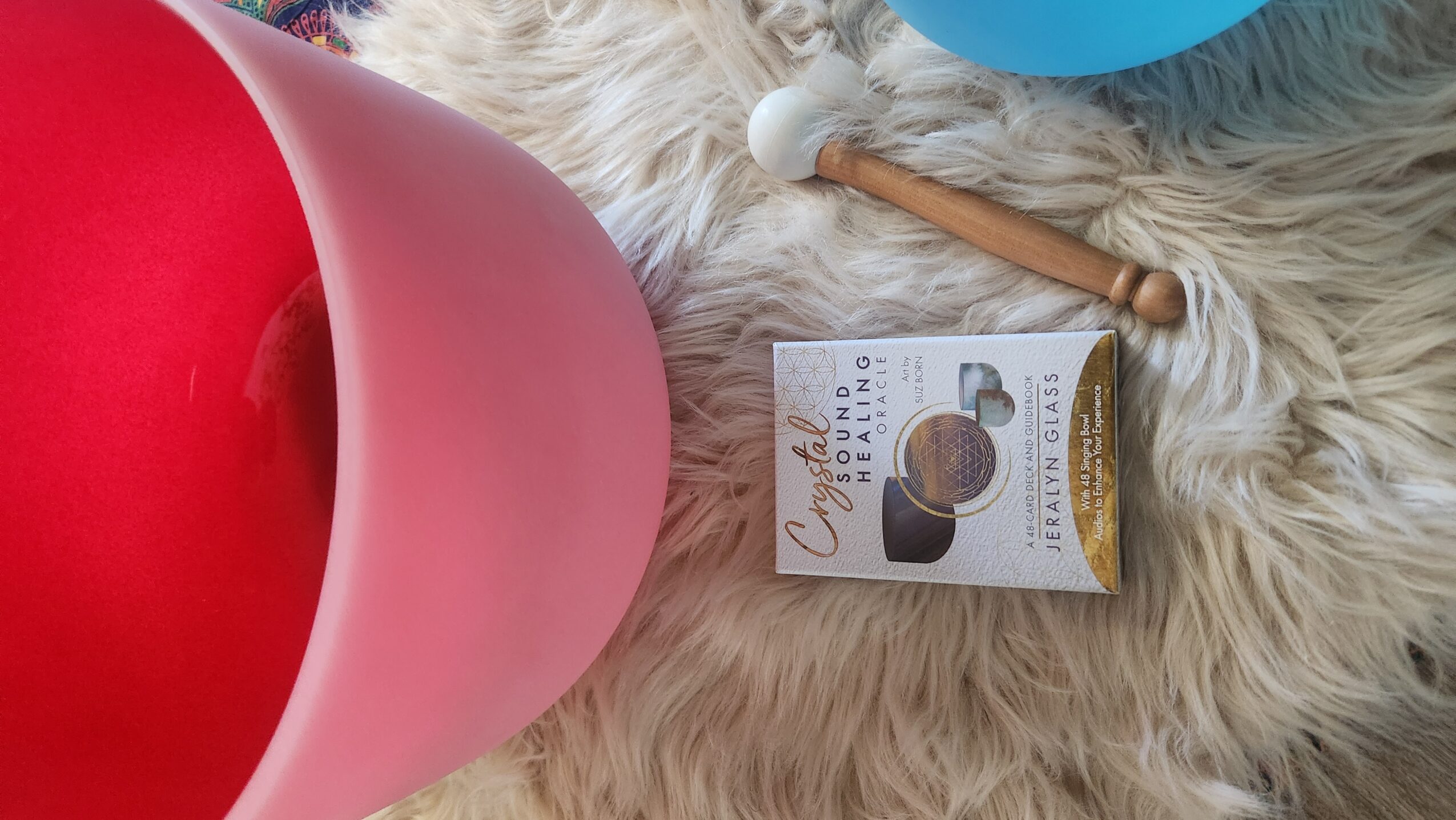 Pink bucket, a box of chocolate, a blue object, and a wooden stick on a furry surface.