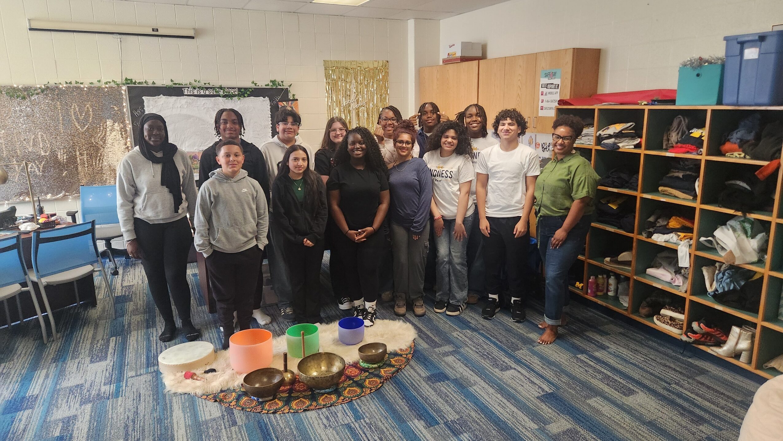 Group of people standing in a room with shelves and a table with bowls, some smiling at the camera.