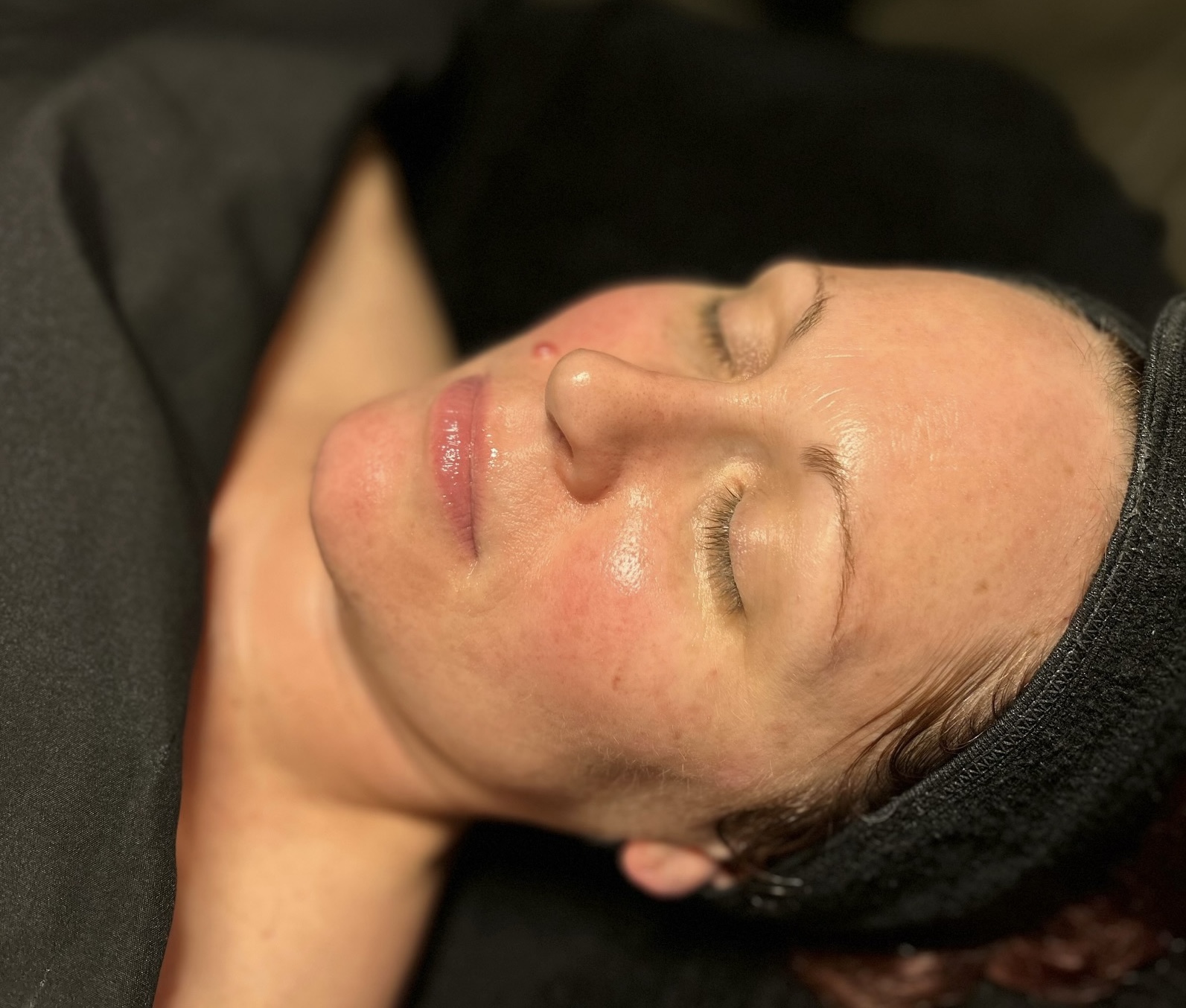Woman with closed eyes, lying down, wearing a black headband, with a relaxed expression.