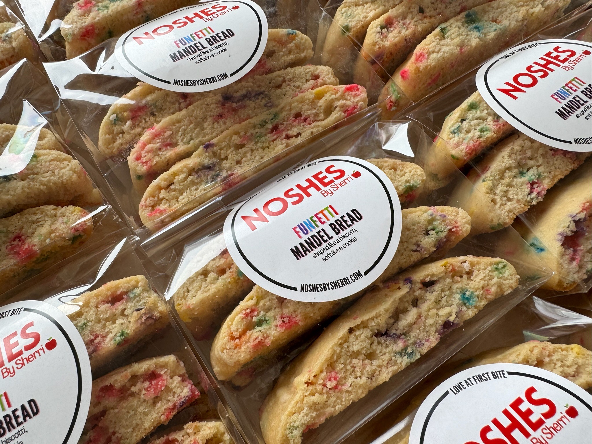 Multiple packaged muffins with colorful sprinkles and a label reading 'NOSHES' and 'MUFFIN BREAD'.