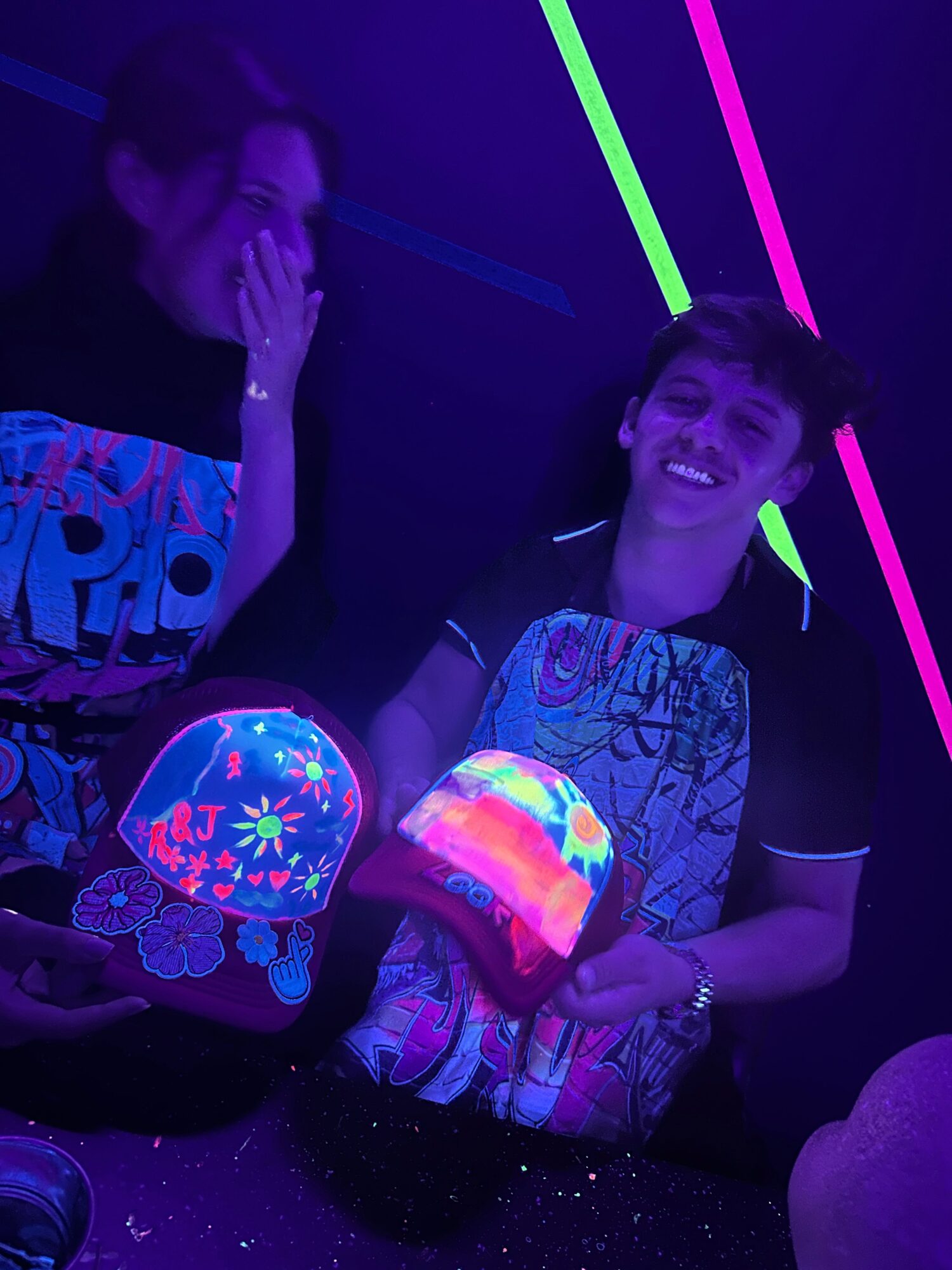 Person smiling holding a glowing bag and a round light-up object, with neon lights in the background.