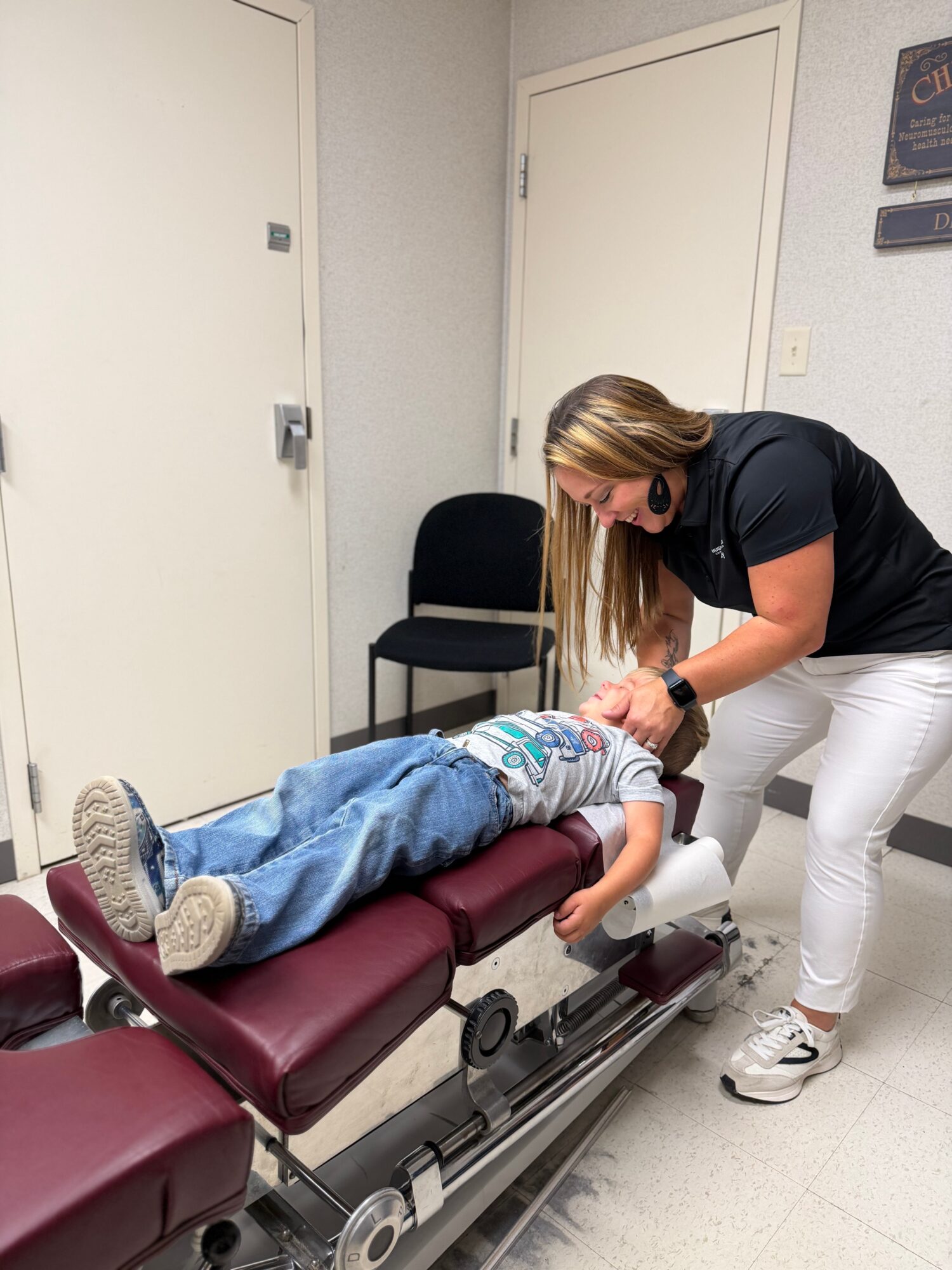 Woman attending to a child lying on a medical examination table in a clinical room.
