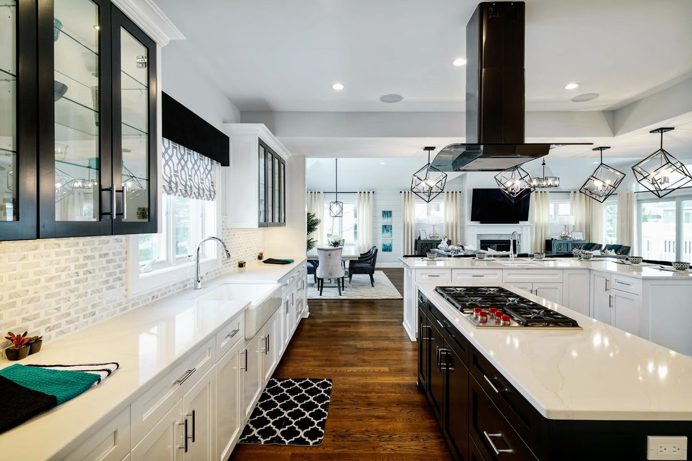 Modern kitchen with white cabinets, black accents, and a central island with a gas stove, hardwood floors, and large windows.