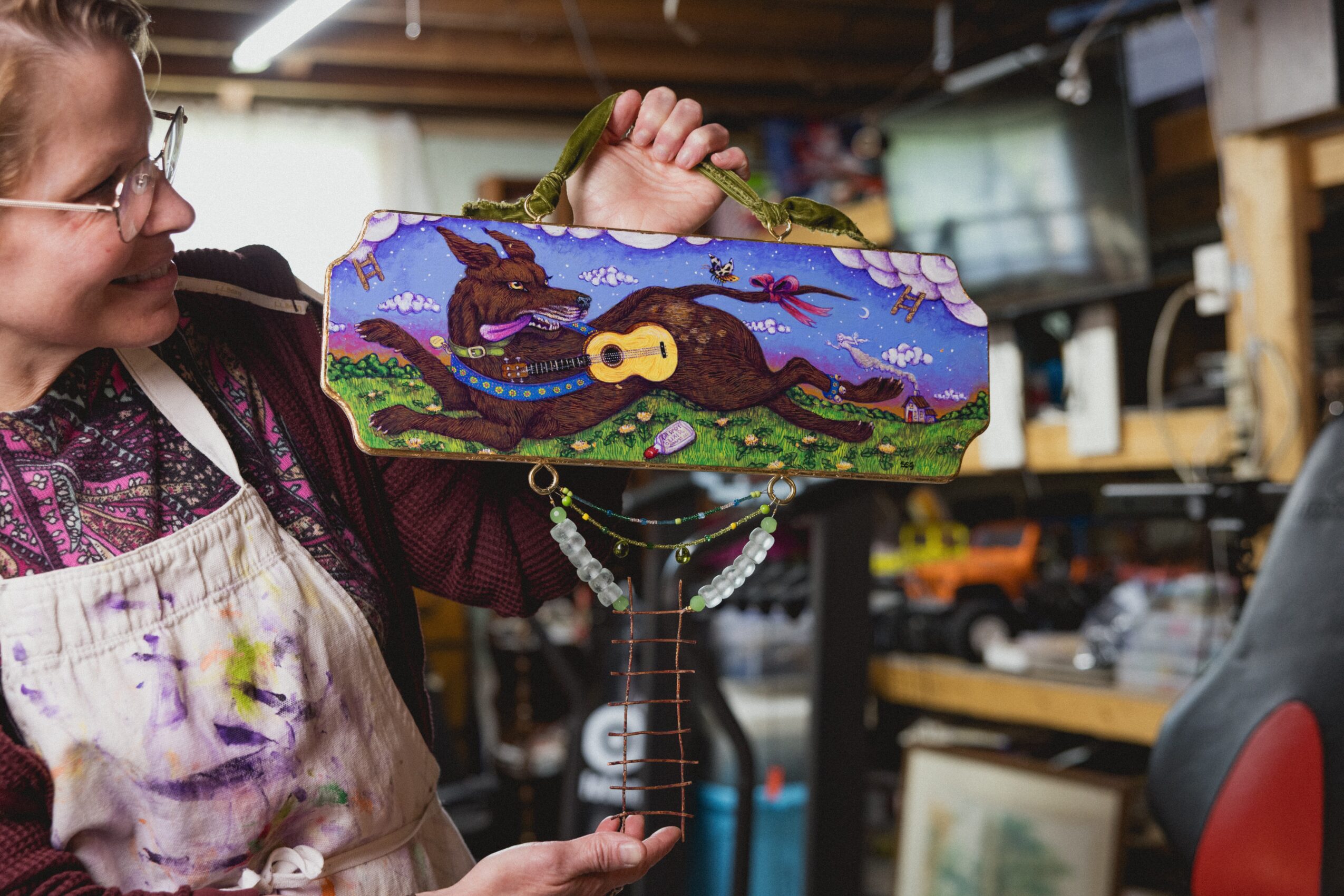 Person holding a colorful, decorated rectangular box with a dragon and landscape design, in a workshop setting.