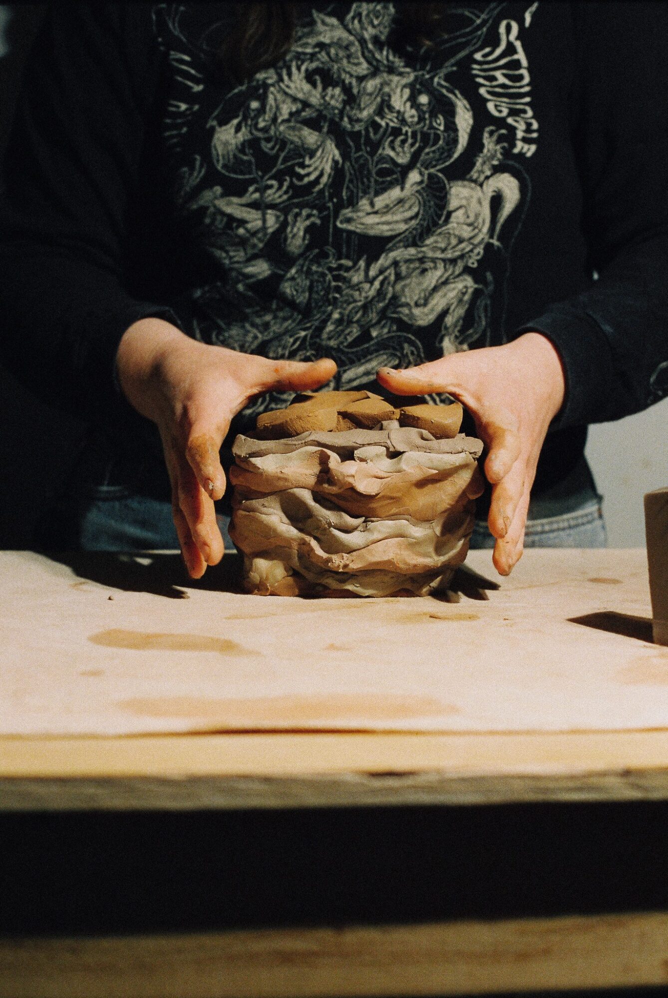 Person holding a layered, textured object with both hands, standing behind a wooden surface.