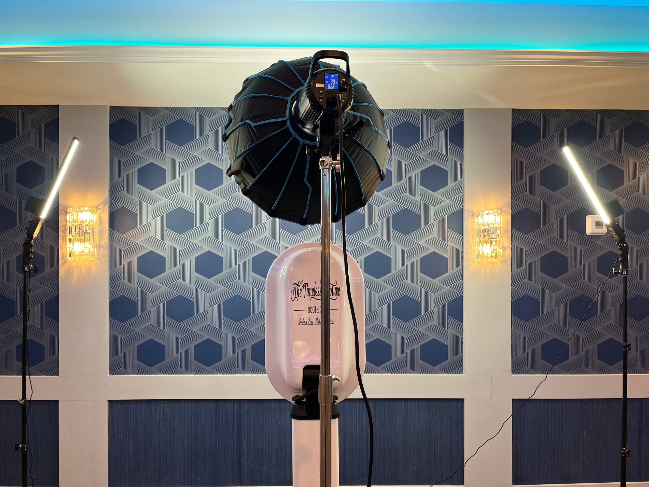 Photography setup with a camera, umbrella light, and two additional lights in a decorated room.