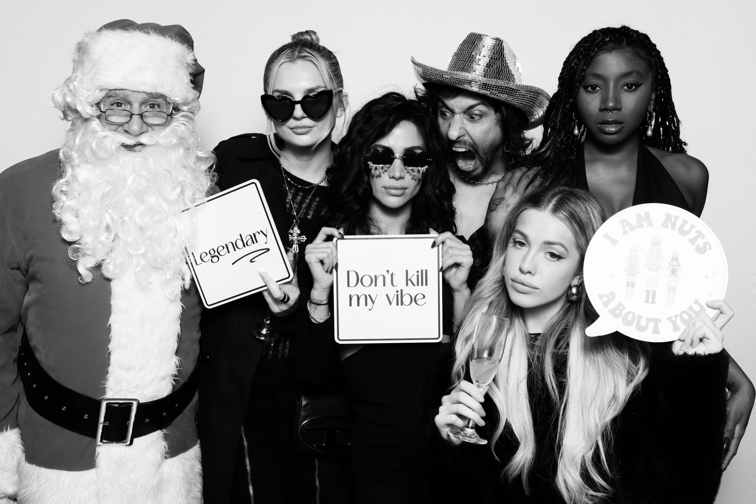 Group of six women and Santa Claus posing, some holding signs, in black and white photo.
