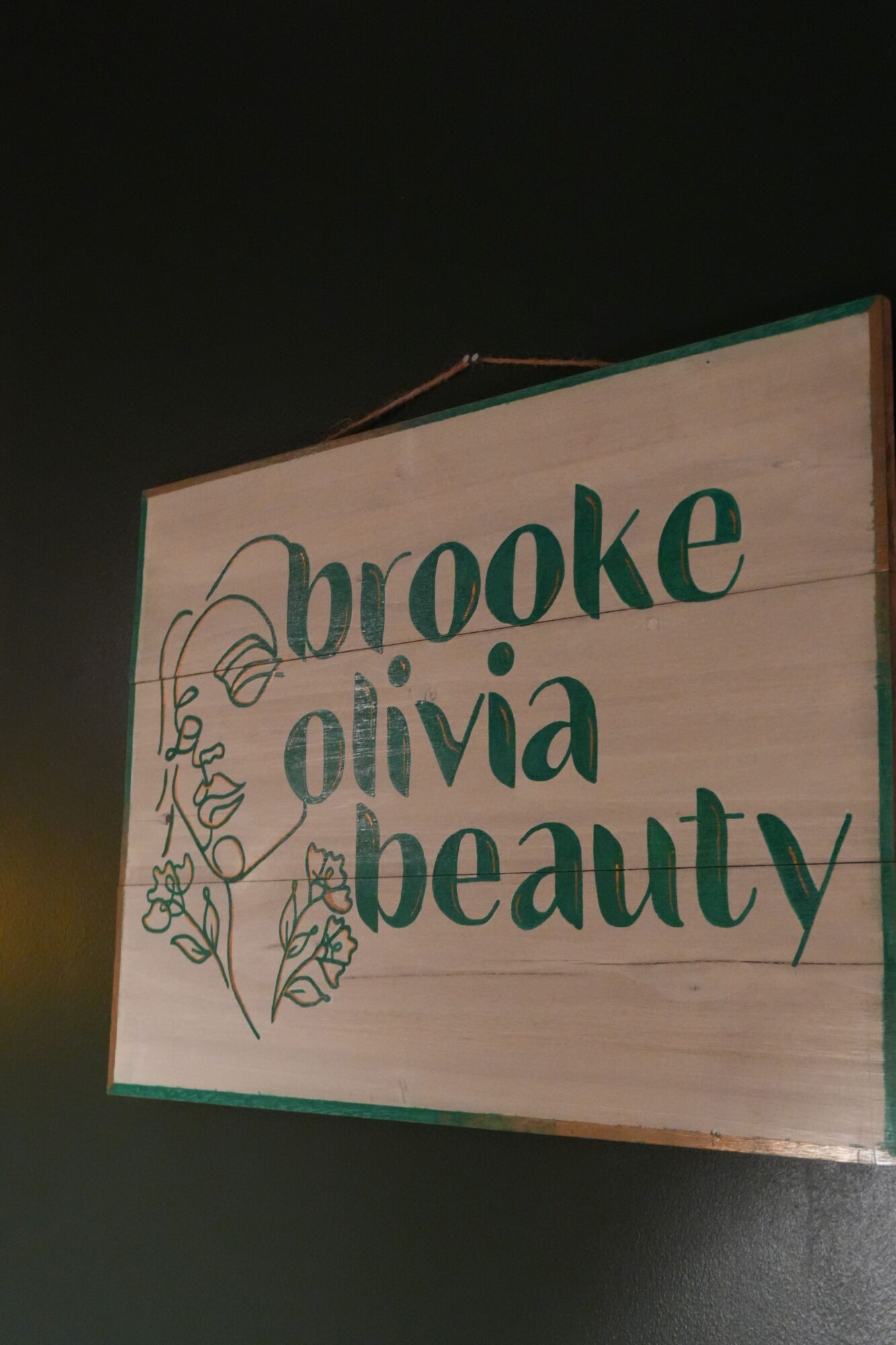 Wooden sign with green text and decorative elements, partially visible, with a dark background.