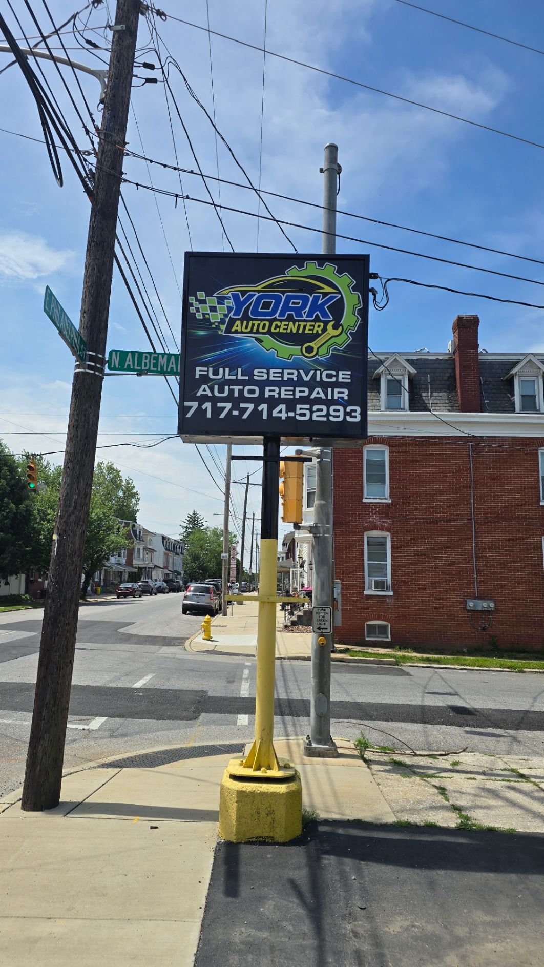 Street corner with a sign for York, a business, on a pole, with buildings and power lines in the background.