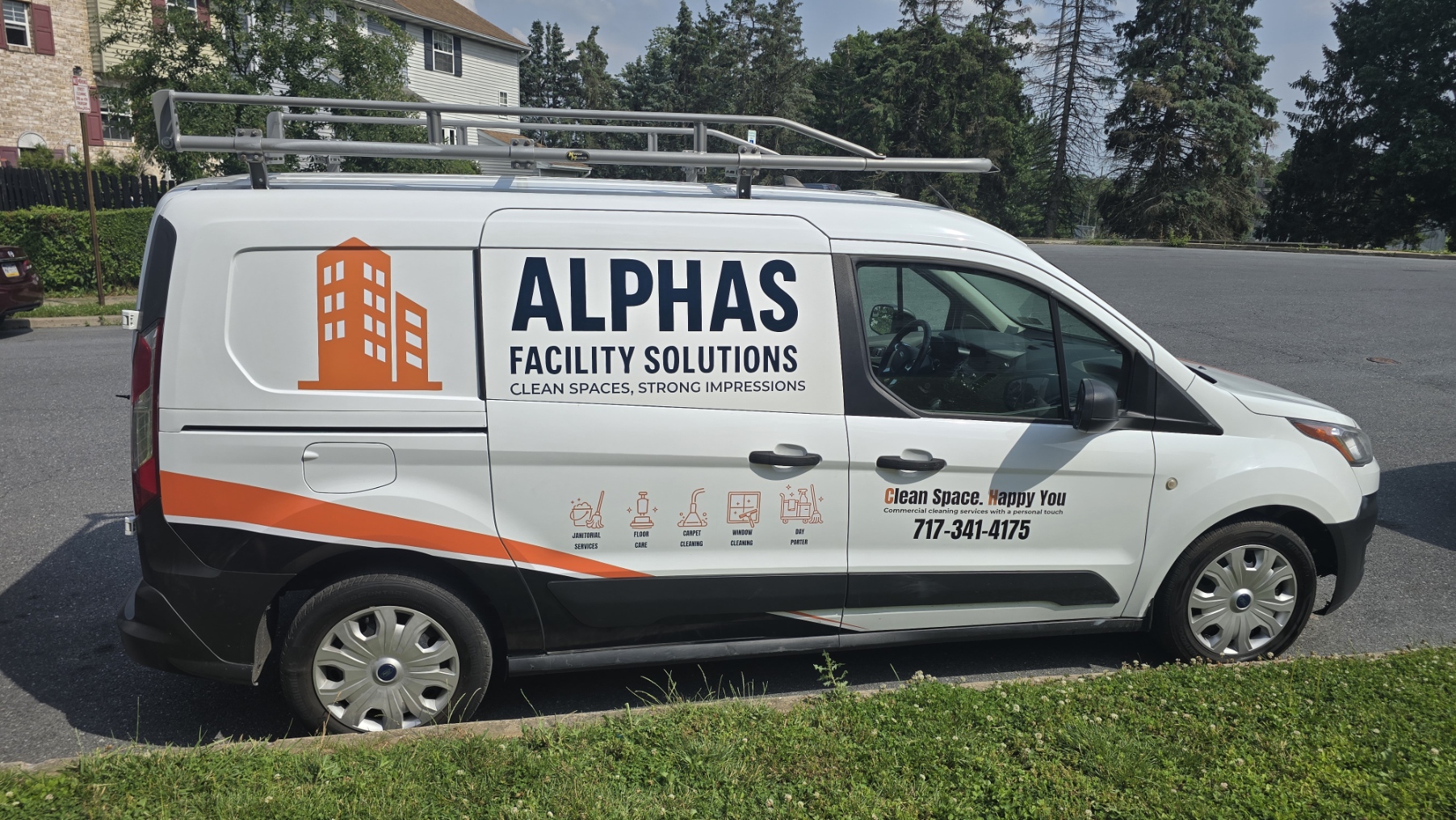 Side view of a white van with ALPHAS Faculty Solutions logo and contact information, parked on grass with trees and houses in background.